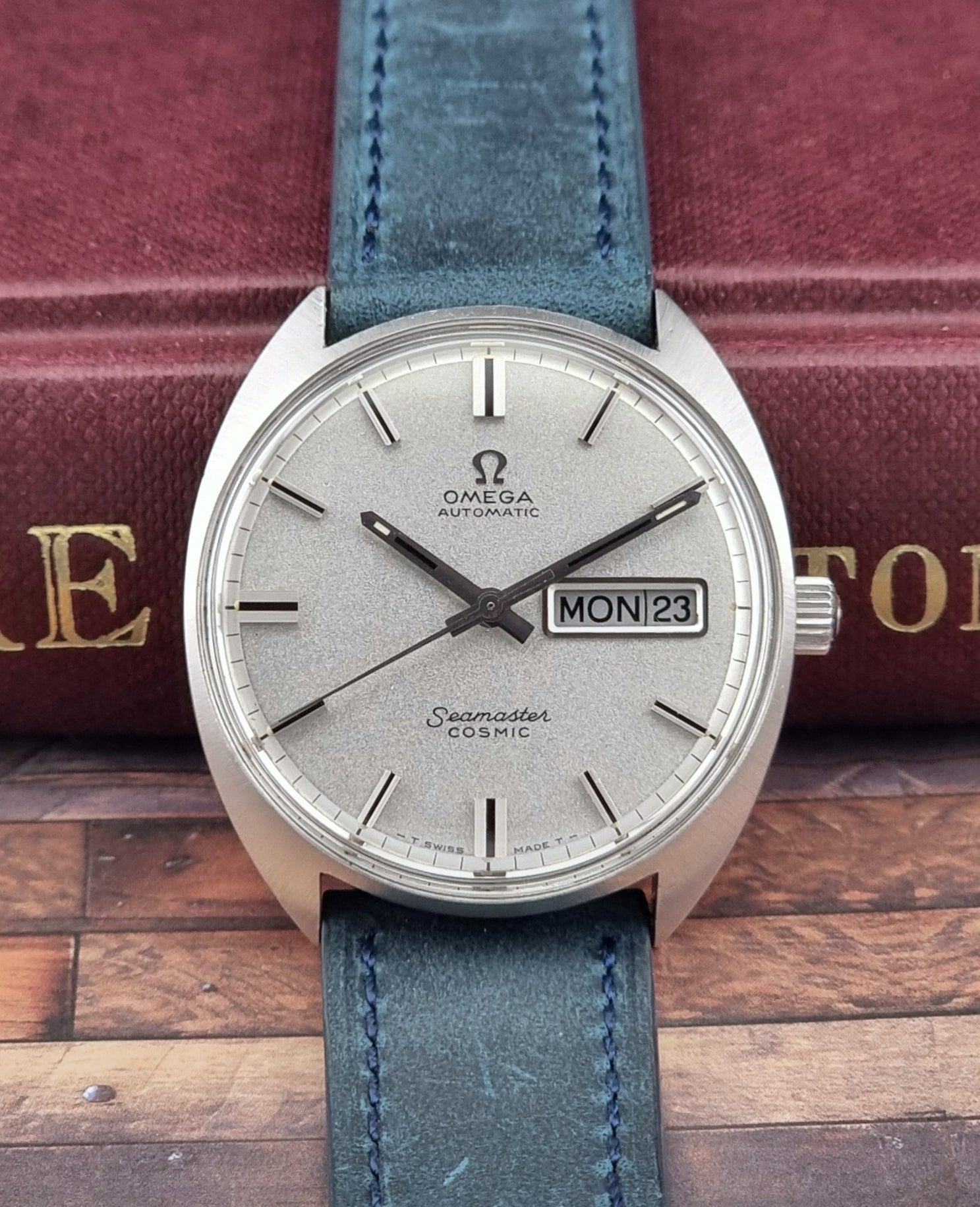 Vintage Omega Seamaster Cosmic watch with blue strap on a wooden surface