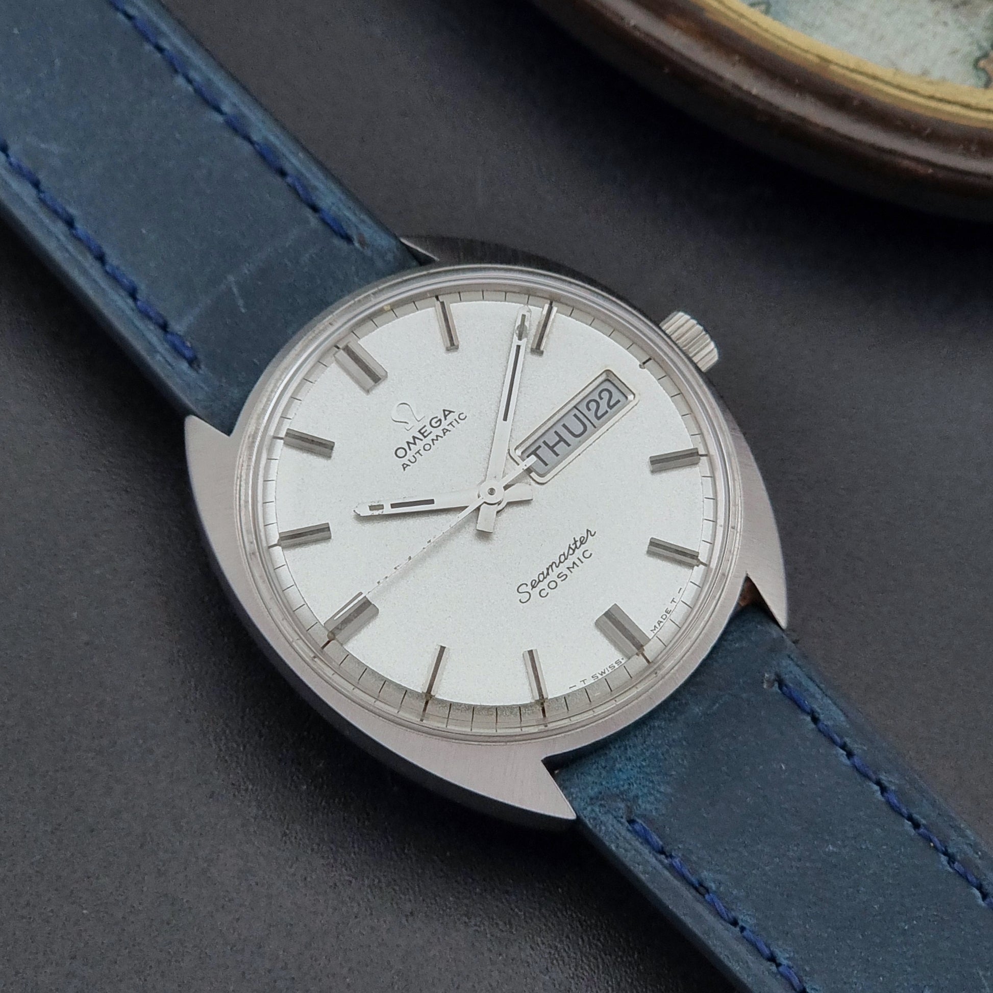 Vintage Omega Wristwatch 166.036 Seamaster Cosmic with blue leather strap on a dark surface close dial view
