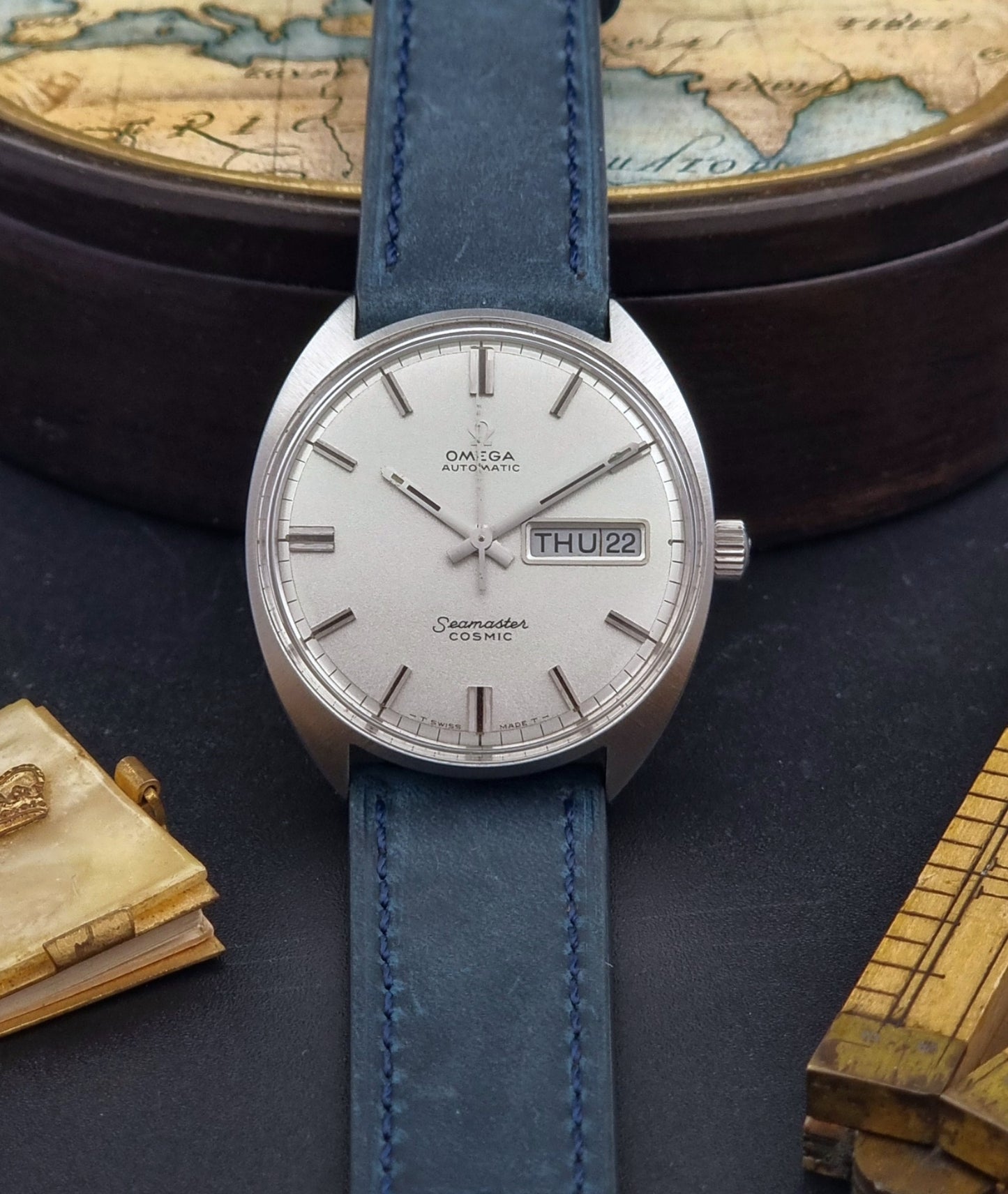 Vintage Omega Wristwatch 166.036 Seamaster Cosmic with blue leather strap on a dark surface front view