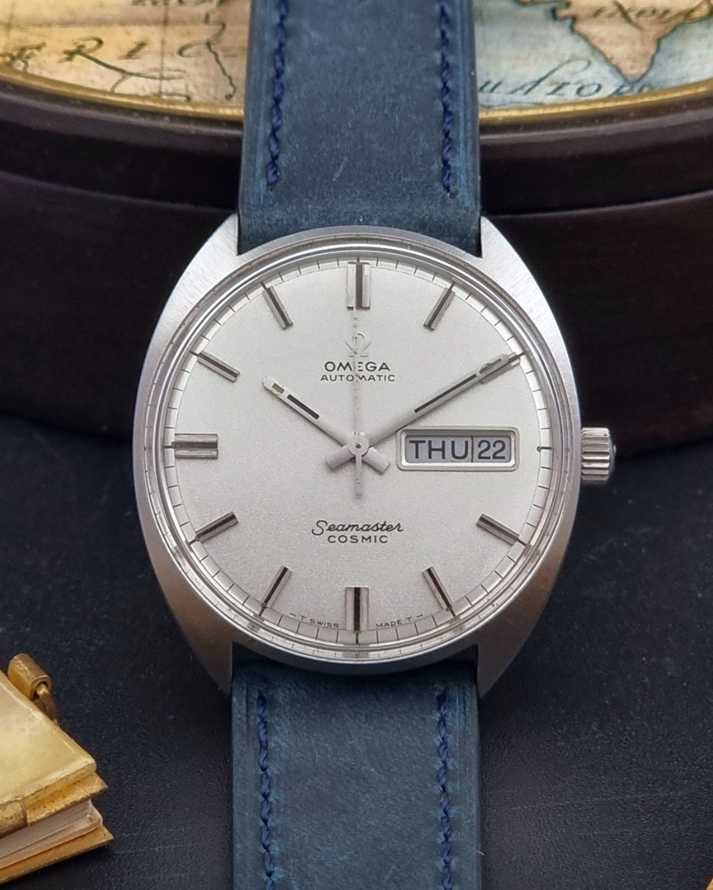 Vintage Omega Wristwatch 166.036 Seamaster Cosmic with blue leather strap on a dark surface close up dial view