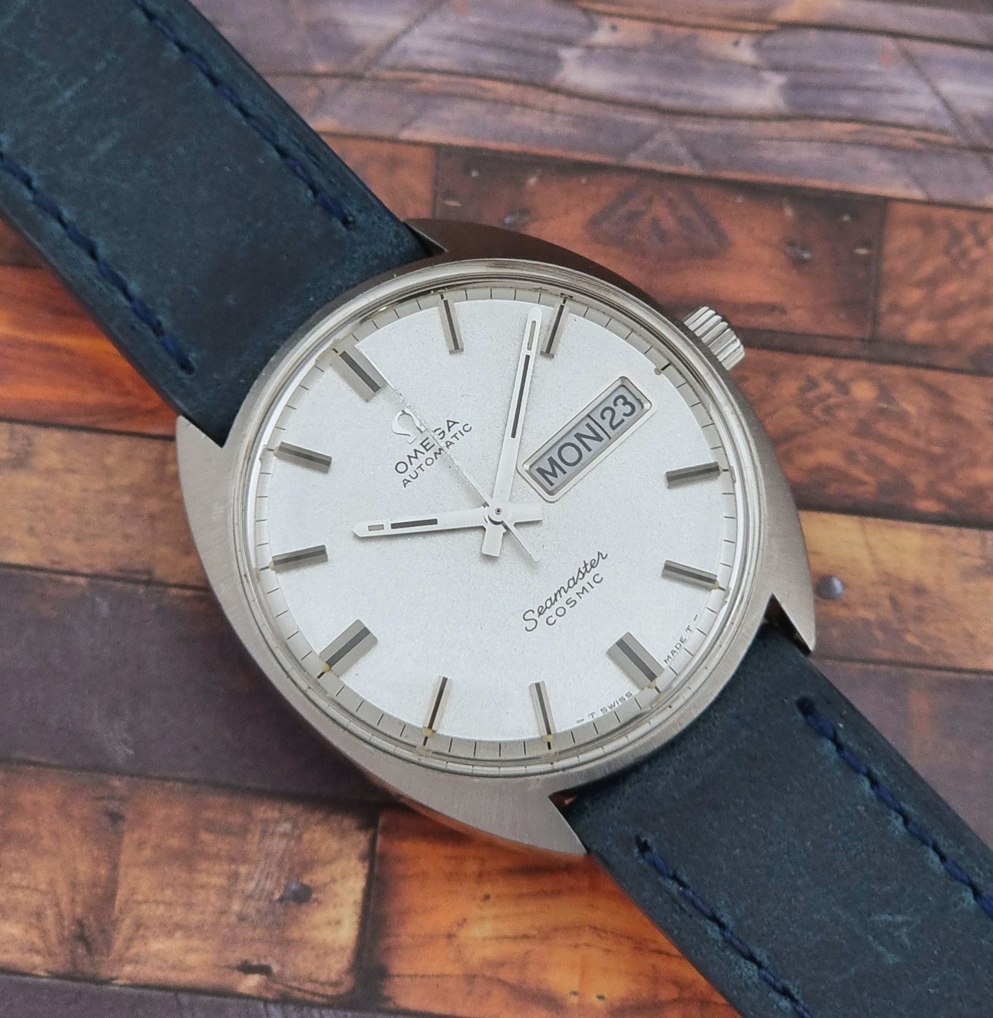 Vintage Omega watch with blue leather strap on a wooden surface