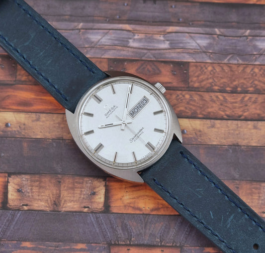 Vintage Omega Seamaster Cosmic watch with black leather strap on a wooden surface