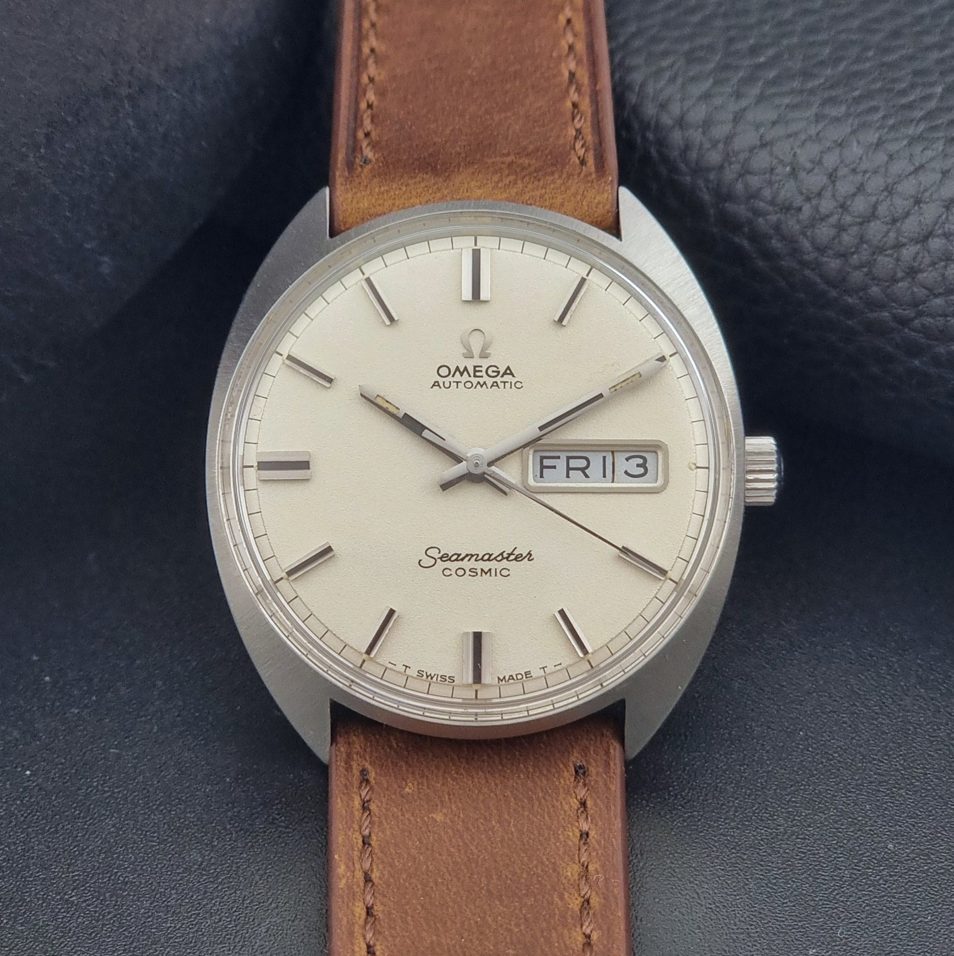 Vintage Omega Seamaster Cosmic 166.036 wristwatch with brown leather strap on a dark background front view