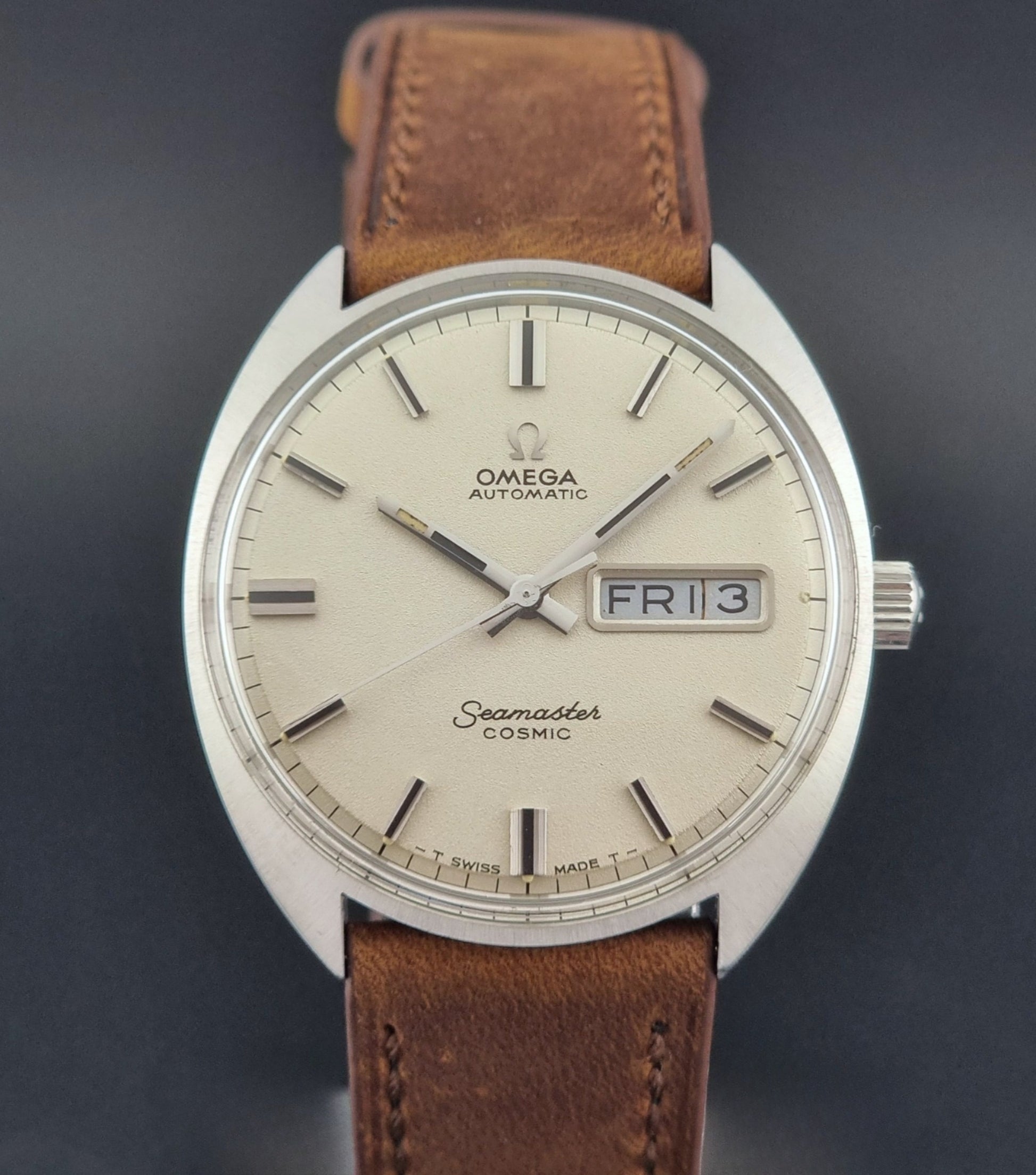 Vintage Omega Seamaster Cosmic 166.036 wristwatch with brown leather strap on a dark background close front view