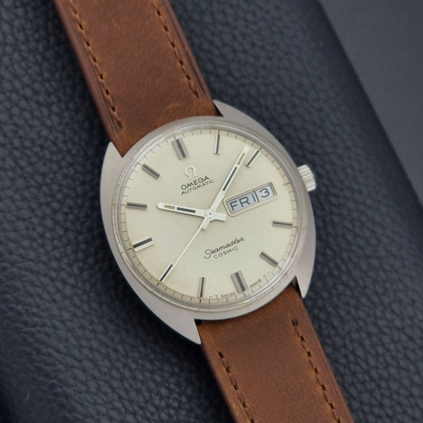 Vintage Omega Seamaster Cosmic 166.036 wristwatch with brown leather strap on a dark background dial view
