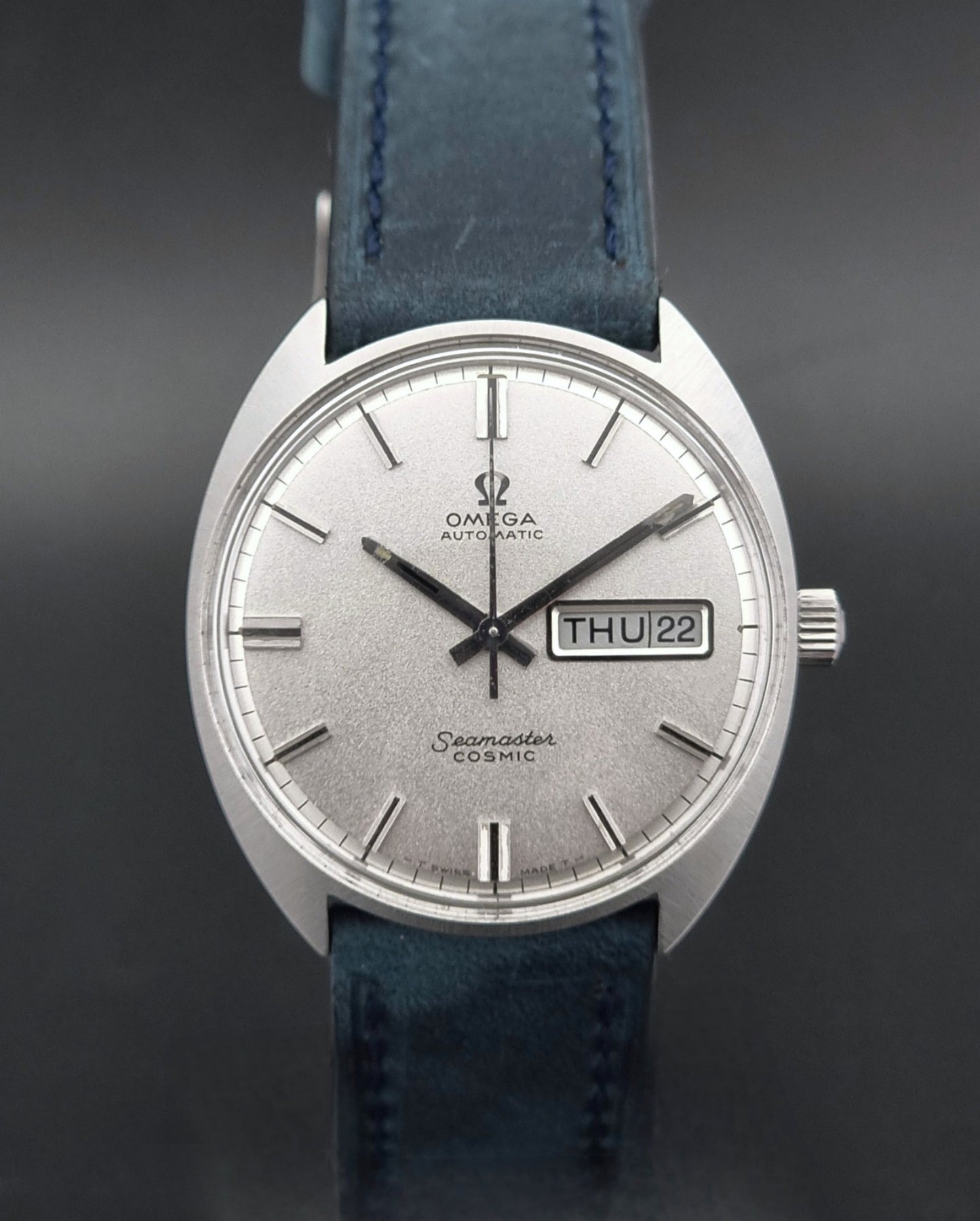 Vintage Omega Wristwatch 166.036 Seamaster Cosmic with blue leather strap on a dark surface dial view