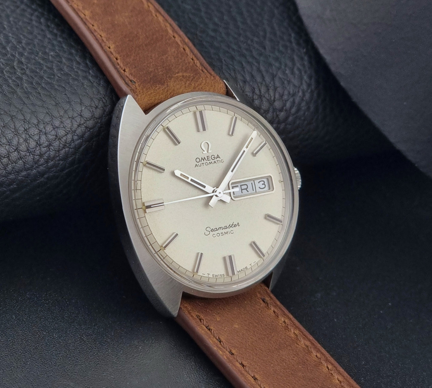 Vintage Omega Seamaster Cosmic 166.036 wristwatch with brown leather strap on a dark background side view