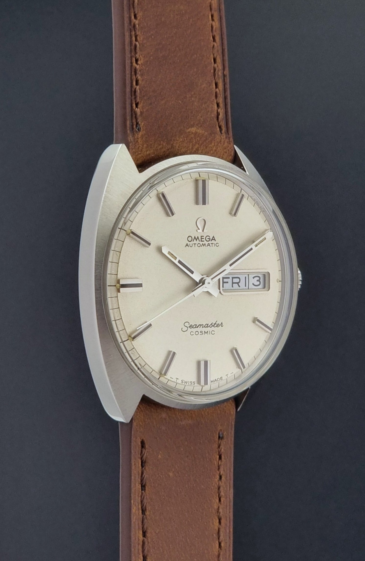 Vintage Omega Seamaster Cosmic 166.036 wristwatch with brown leather strap on a dark background side profile view