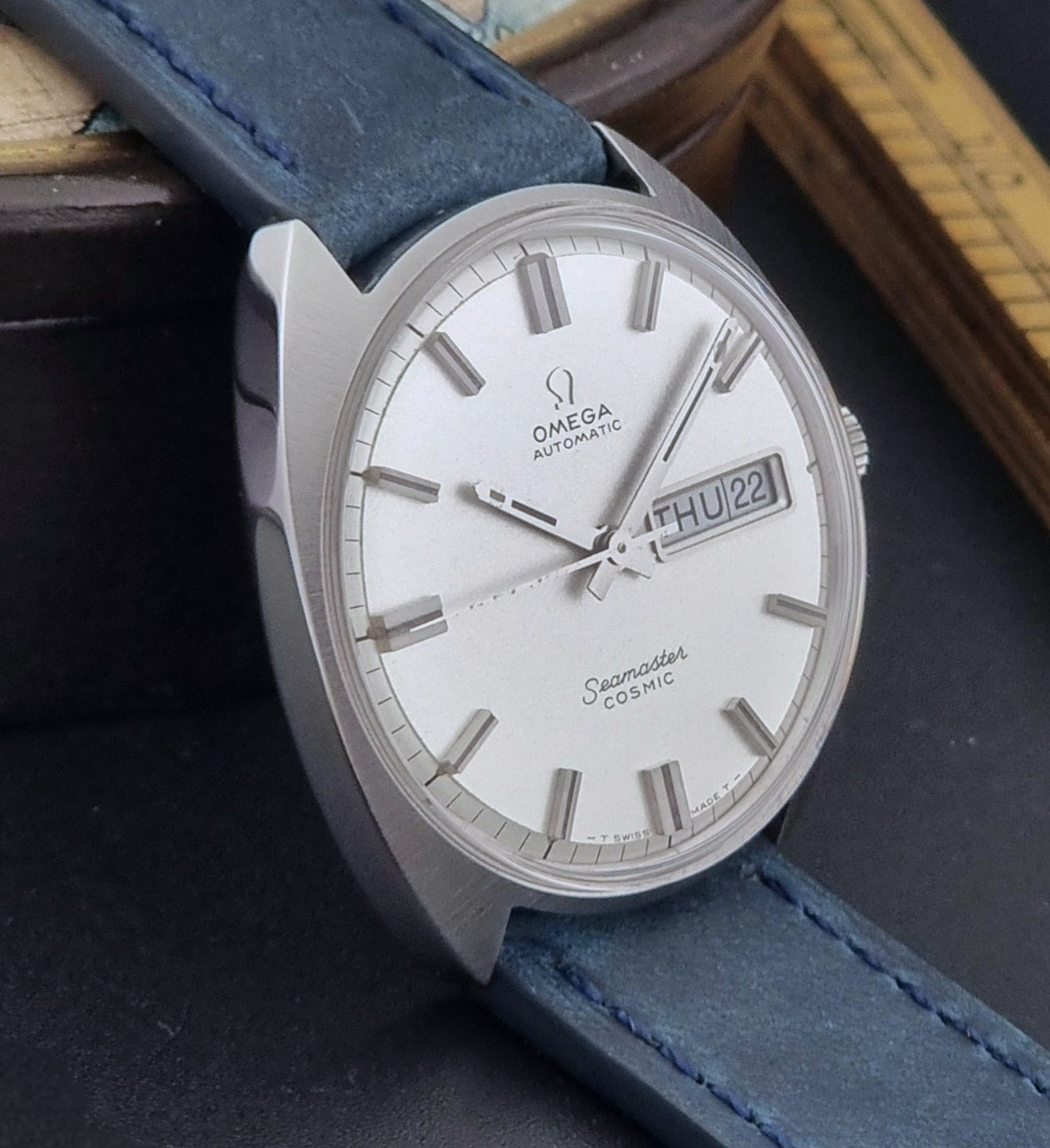 Vintage Omega Wristwatch 166.036 Seamaster Cosmic with blue leather strap on a dark surface side view