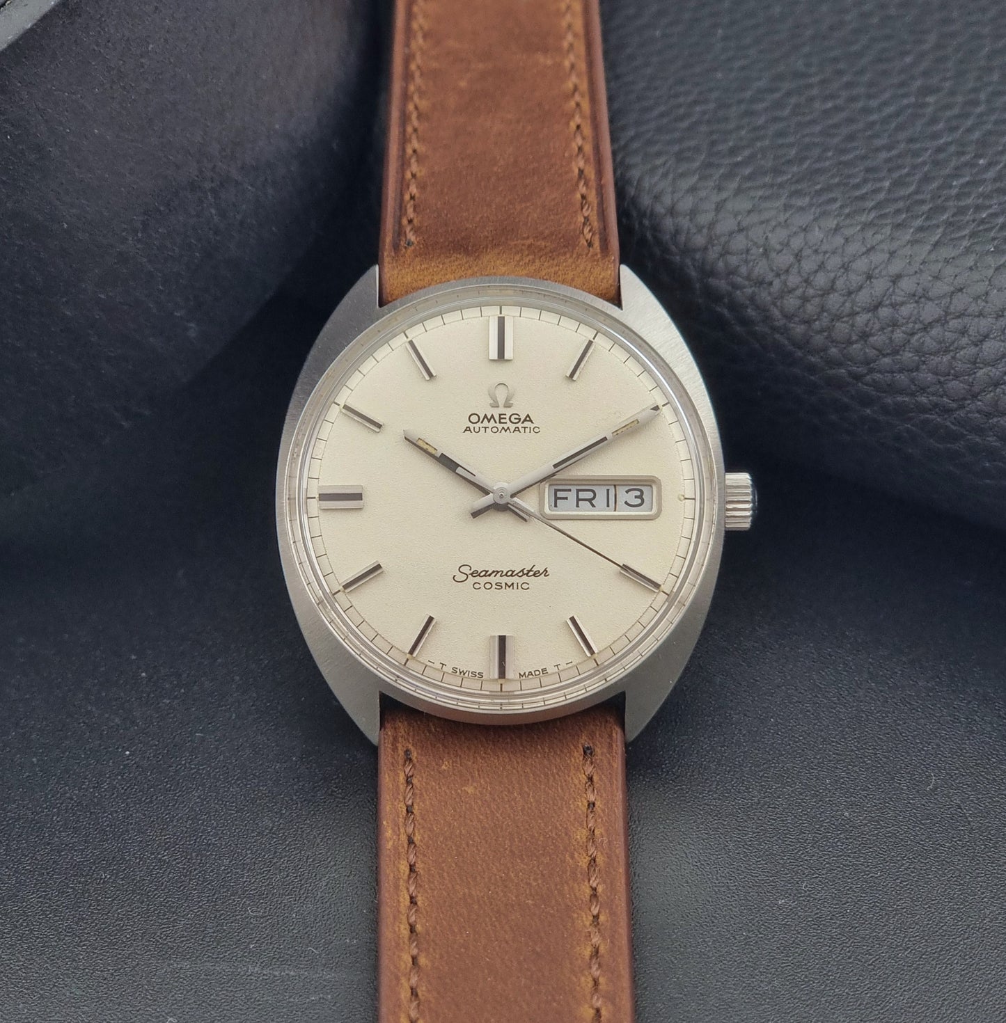 Vintage Omega Seamaster Cosmic 166.036 wristwatch with brown leather strap on a dark background close dial view