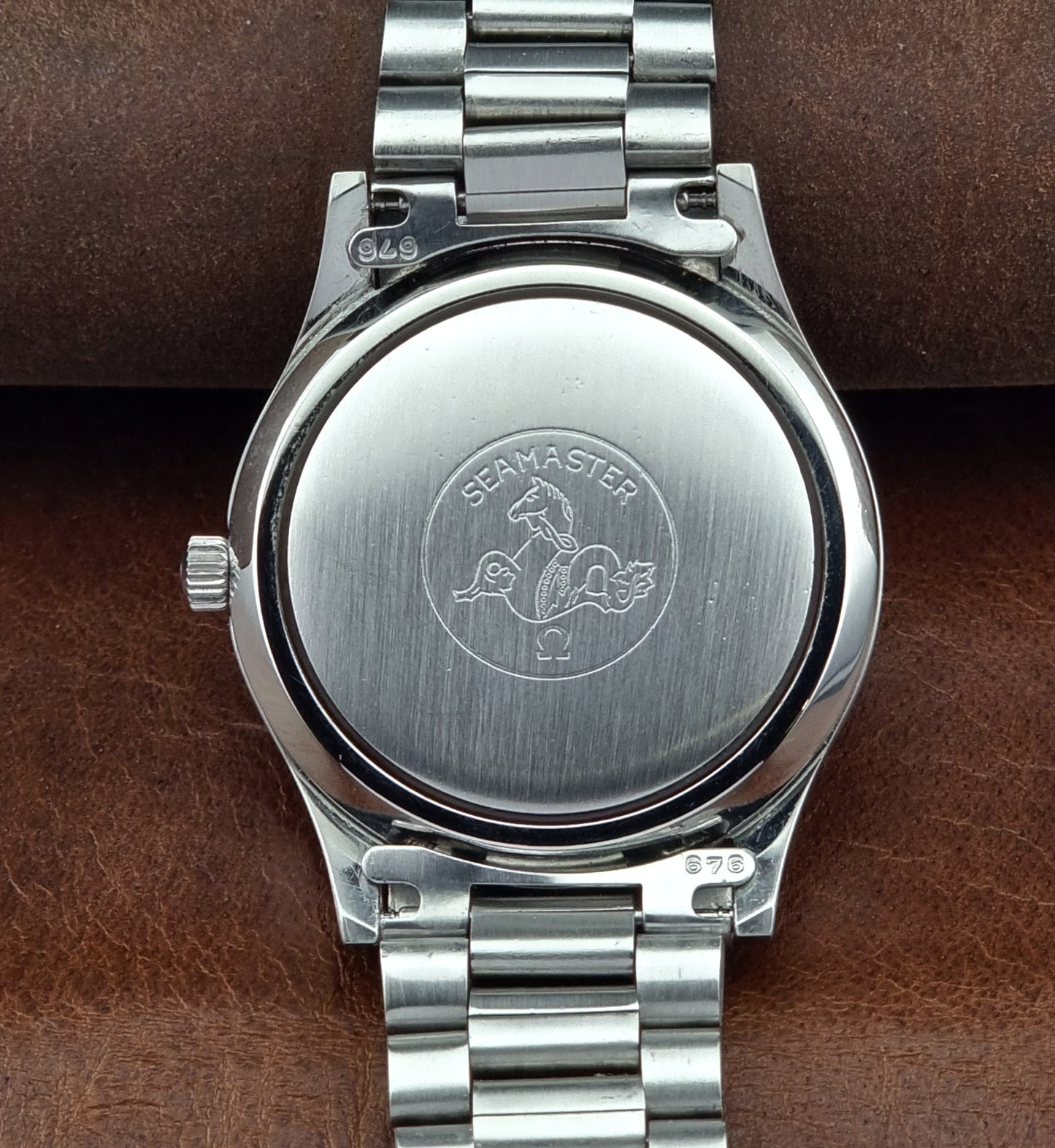 Close-up of a silver watch with 'Seamaster' branding on a brown leather background