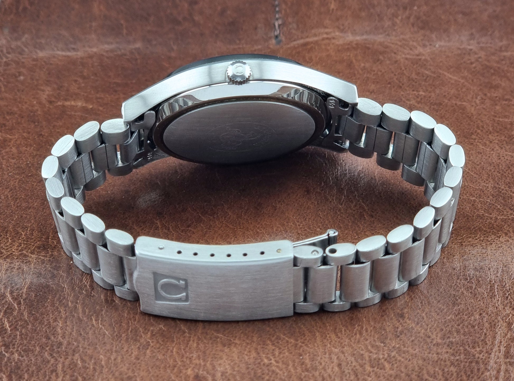 Silver metal watch on a brown leather background