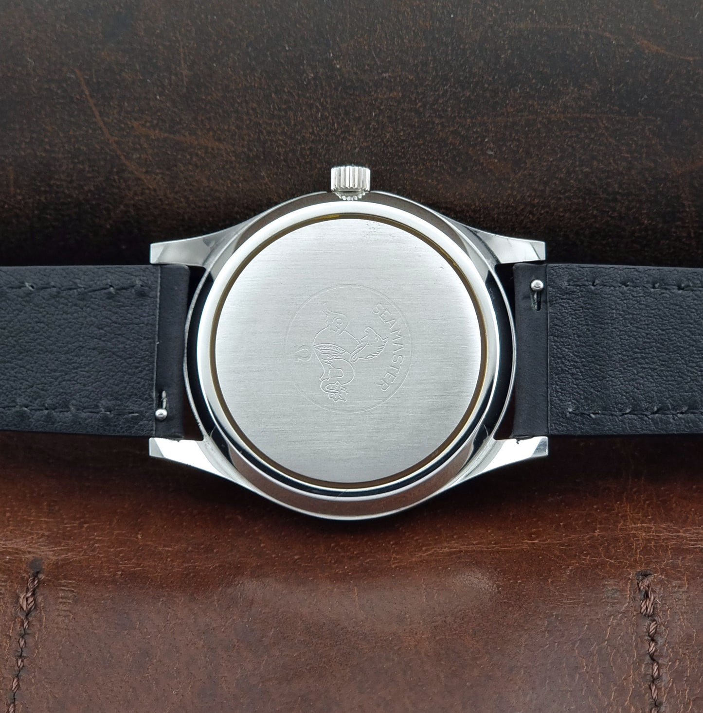 Vintage Omega Wristwatch Seamaster Cosmic 2000 Jumbo 166.128 black leather strap on a brown leather surface case back view