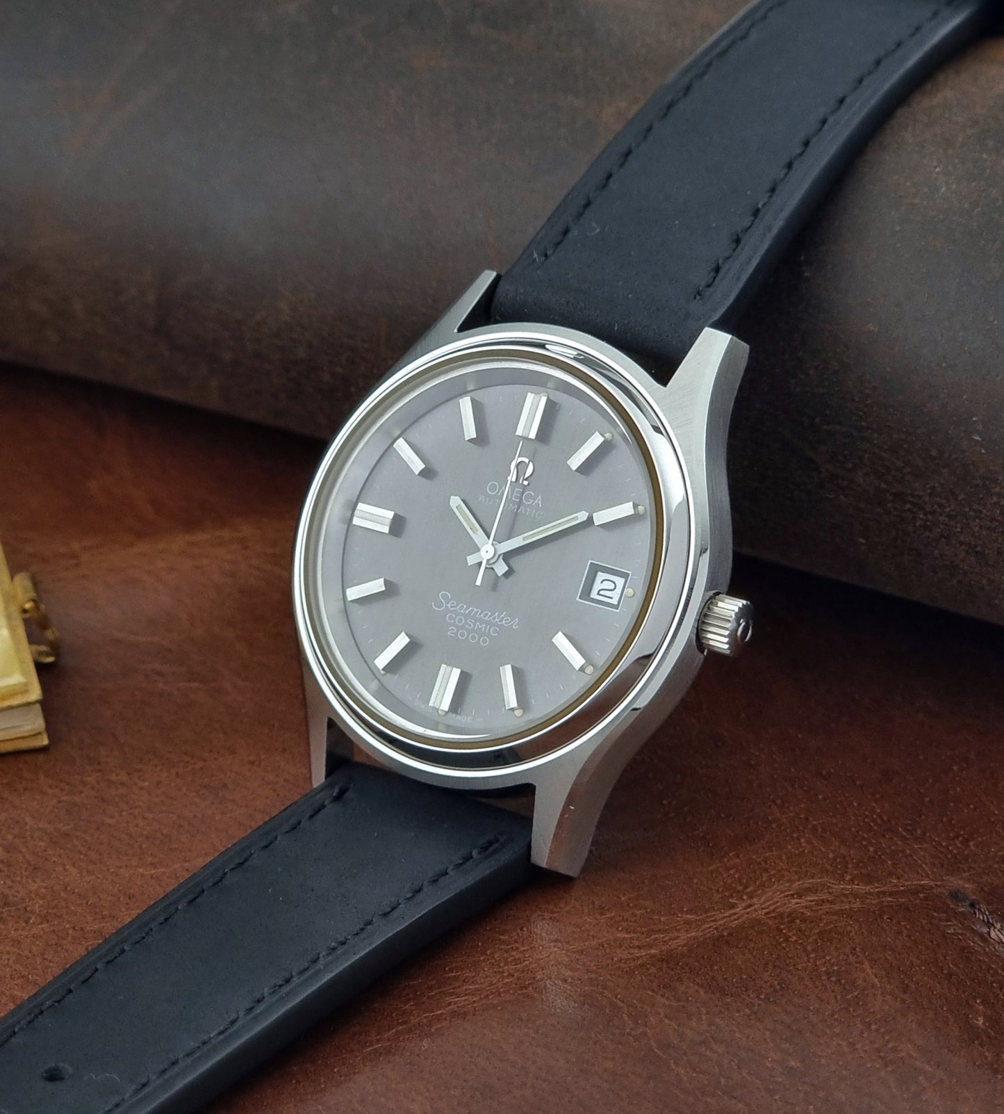 Vintage Omega Wristwatch Seamaster Cosmic 2000 Jumbo 166.128 black leather strap on a brown leather surface crown view