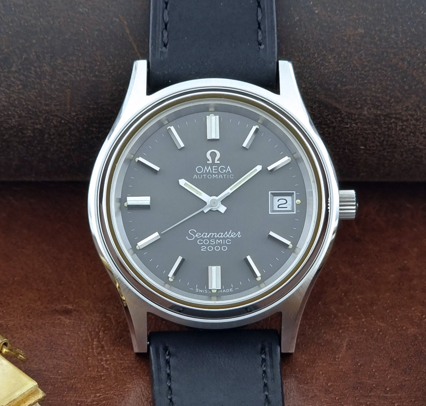 Vintage Omega Wristwatch Seamaster Cosmic 2000 Jumbo 166.128 black leather strap on a brown leather surface close up dial view