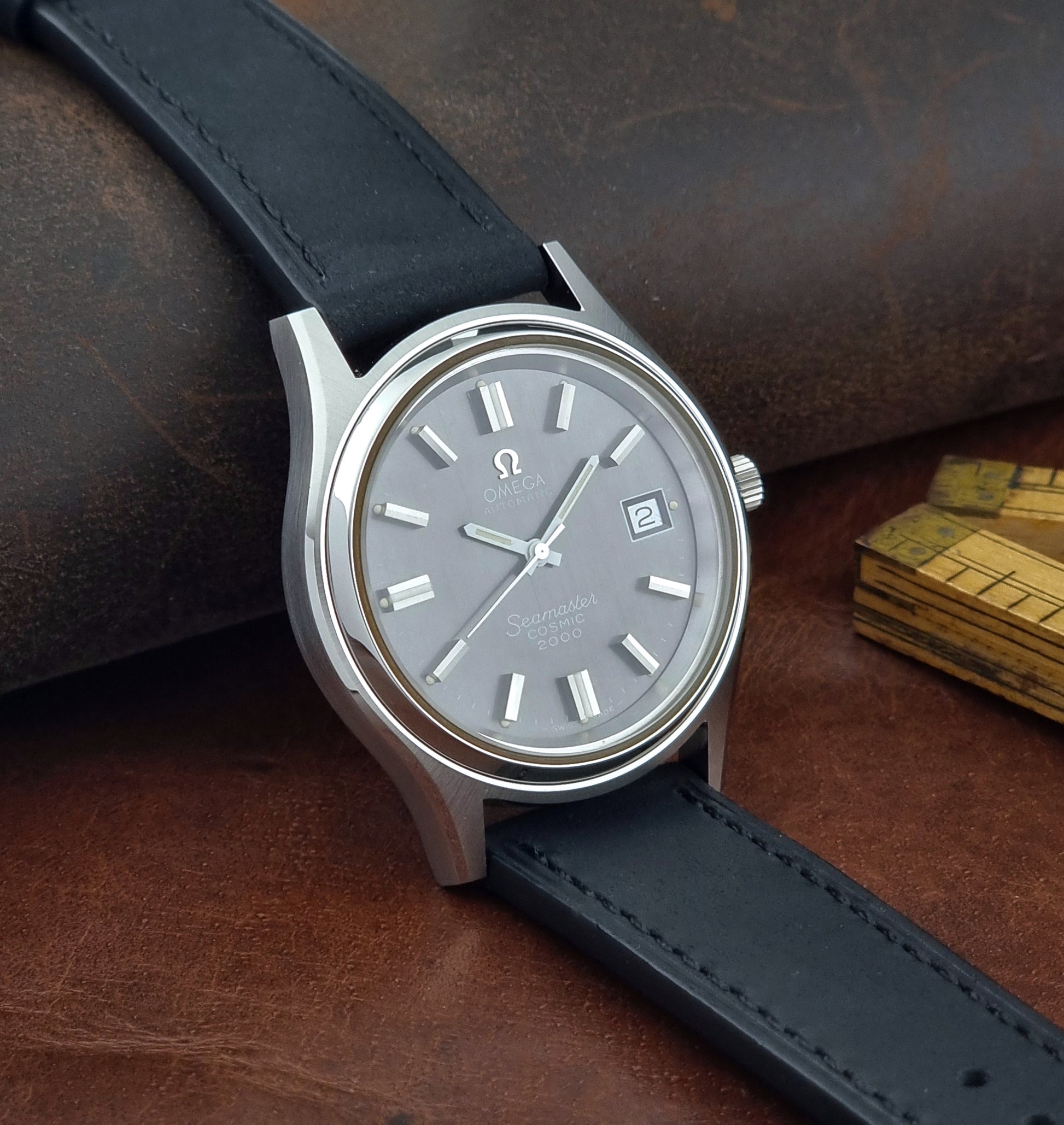 Vintage Omega Wristwatch Seamaster Cosmic 2000 Jumbo 166.128 black leather strap on a brown leather surface side view