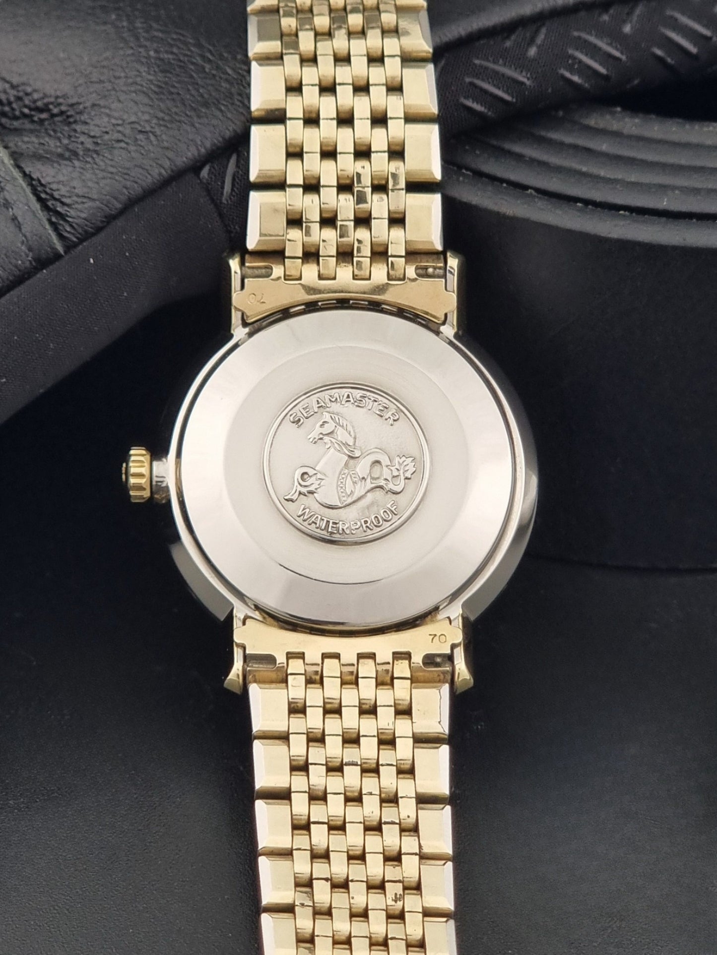 Vintage Omega Wristwatch Seamaster De-ville 166.020 with gold omega bracelet, gold case, on a dark gray background case back view