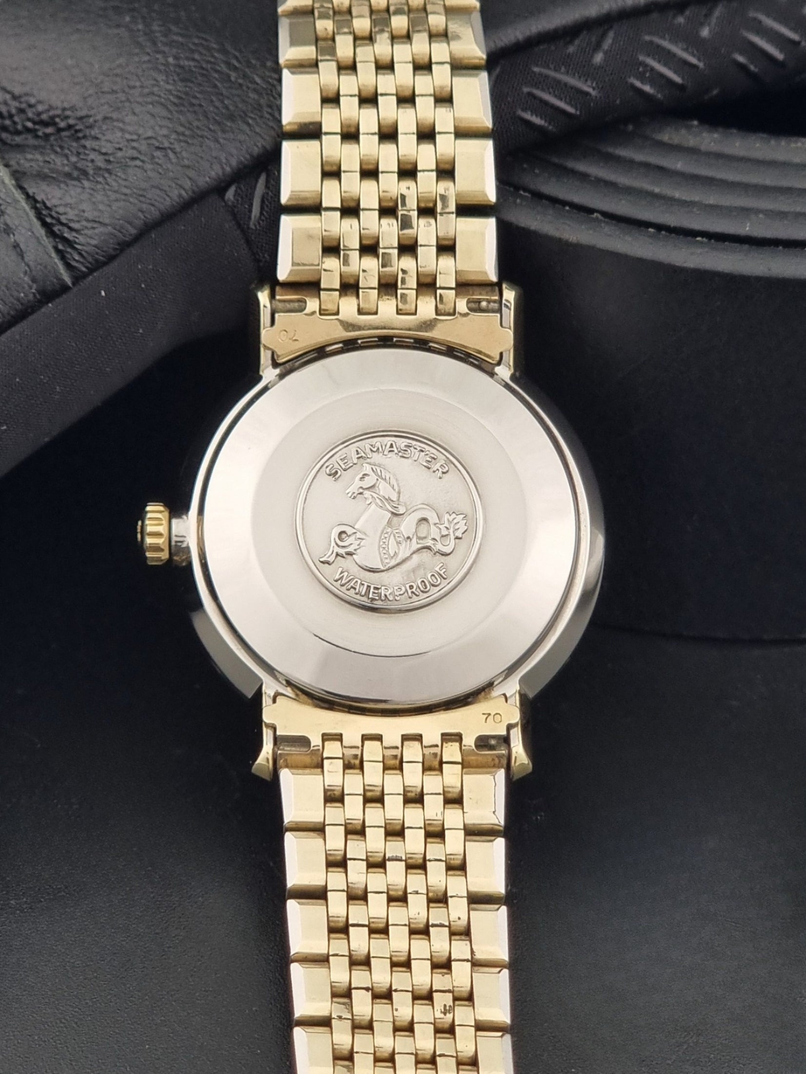 Vintage Omega Wristwatch Seamaster De-ville 166.020 with gold omega bracelet, gold case, on a dark gray background case back view