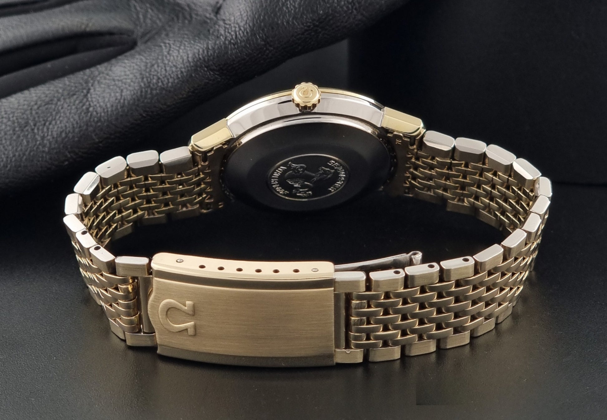 Vintage Omega Wristwatch Seamaster De-ville 166.020 with gold omega bracelet, gold case, on a dark gray background clasp view