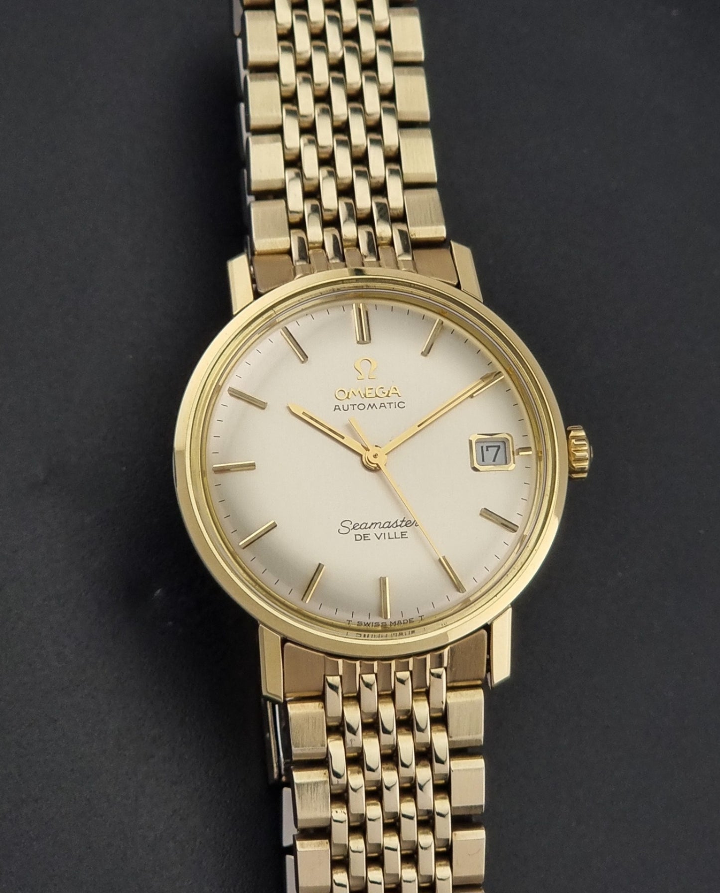 Vintage Omega Wristwatch Seamaster De-ville 166.020 with gold omega bracelet, gold case, on a dark gray background close dial view