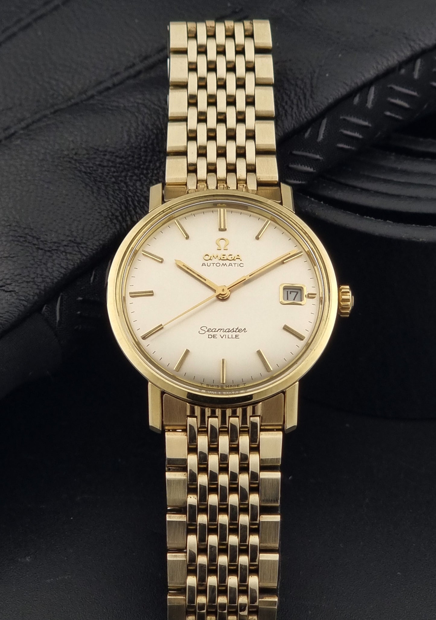 Vintage Omega Wristwatch Seamaster De-ville 166.020 with gold omega bracelet, gold case, on a dark gray background dial view