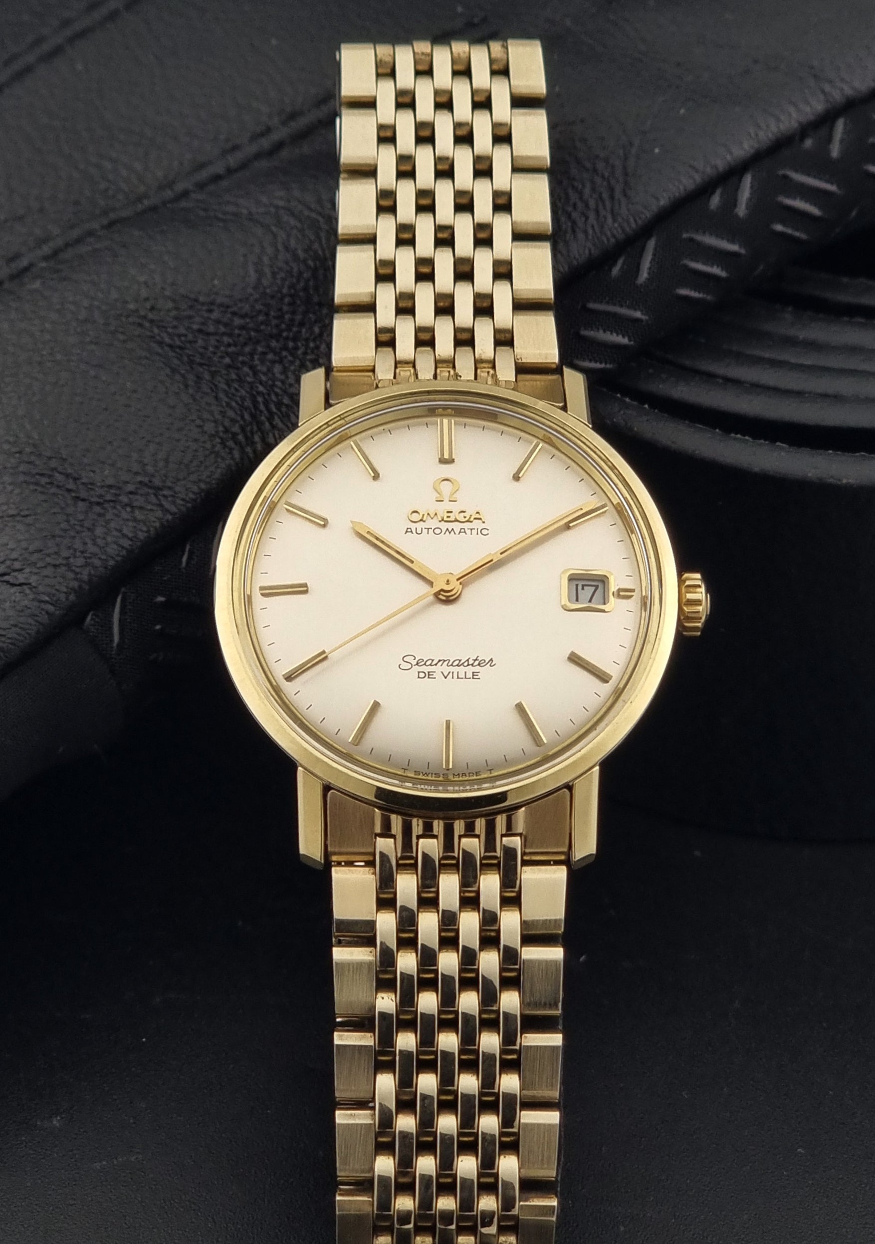 Vintage Omega Wristwatch Seamaster De-ville 166.020 with gold omega bracelet, gold case, on a dark gray background dial view