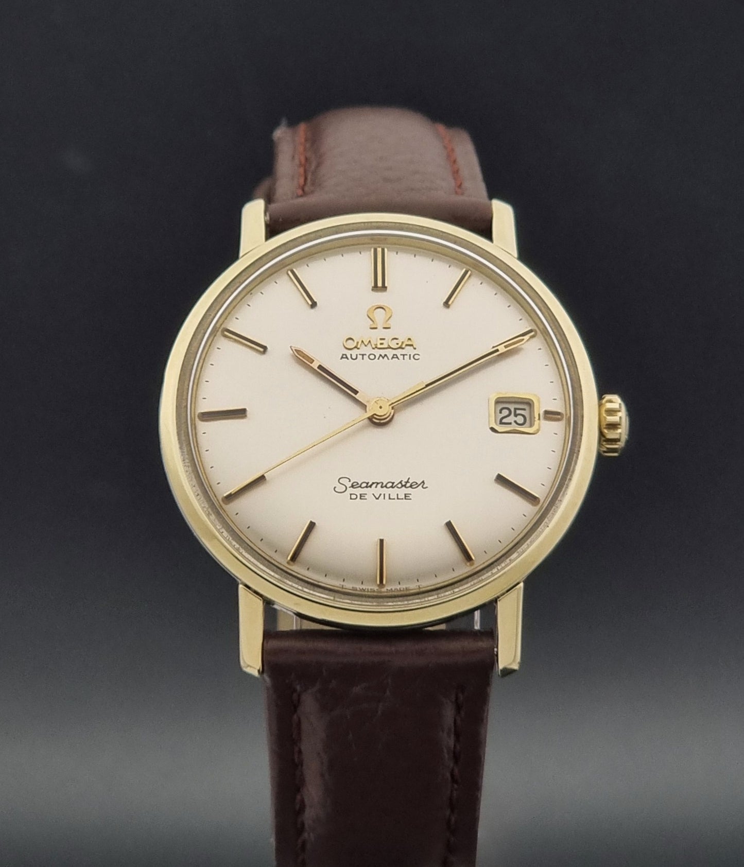 Vintage Omega Wristwatch Seamaster De-ville 166.020 with a brown textured leather strap, gold case, on a dark gray background close dial view