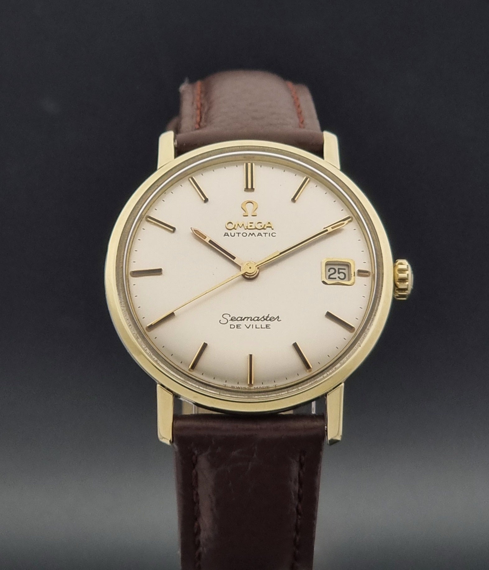 Vintage Omega Wristwatch Seamaster De-ville 166.020 with a brown textured leather strap, gold case, on a dark gray background close dial view