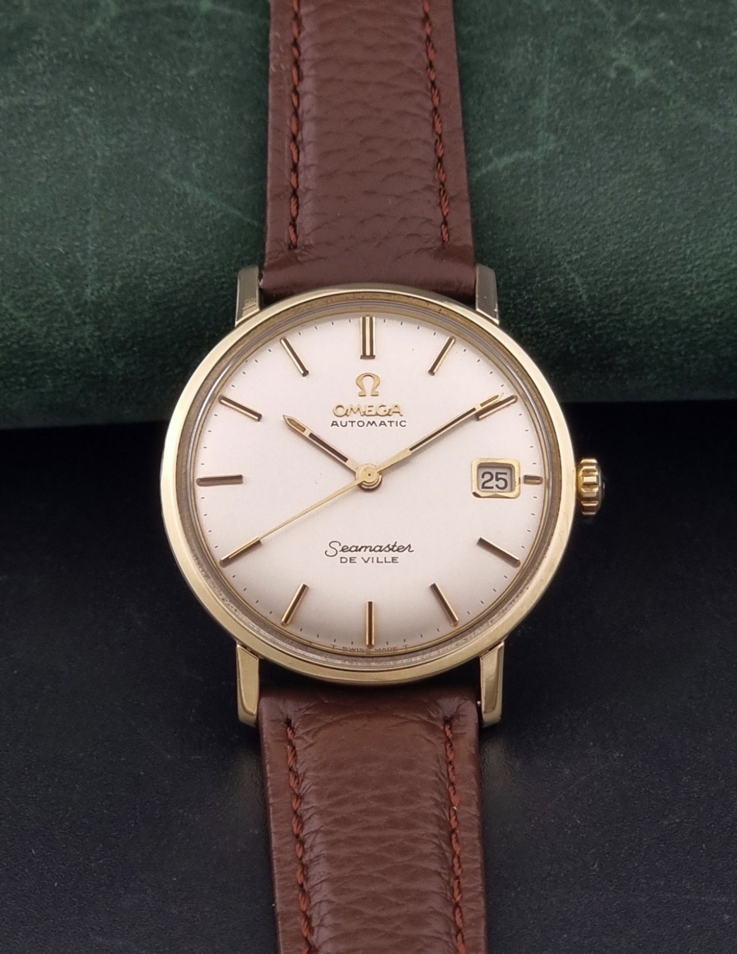 Vintage Omega Wristwatch Seamaster De-ville 166.020 with a brown textured leather strap, gold case, on a dark gray background dial view