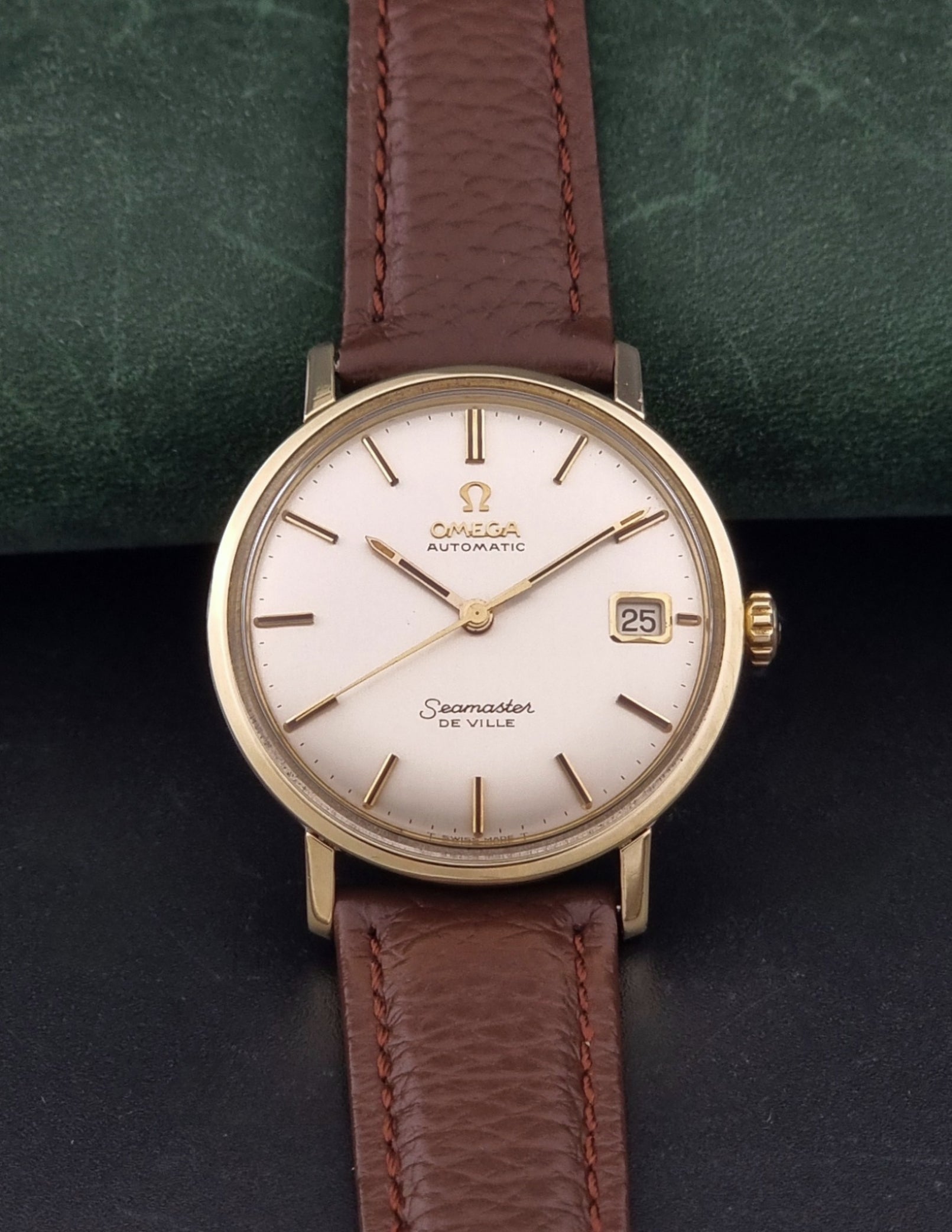 Vintage Omega Wristwatch Seamaster De-ville 166.020 with a brown textured leather strap, gold case, on a dark gray background dial view