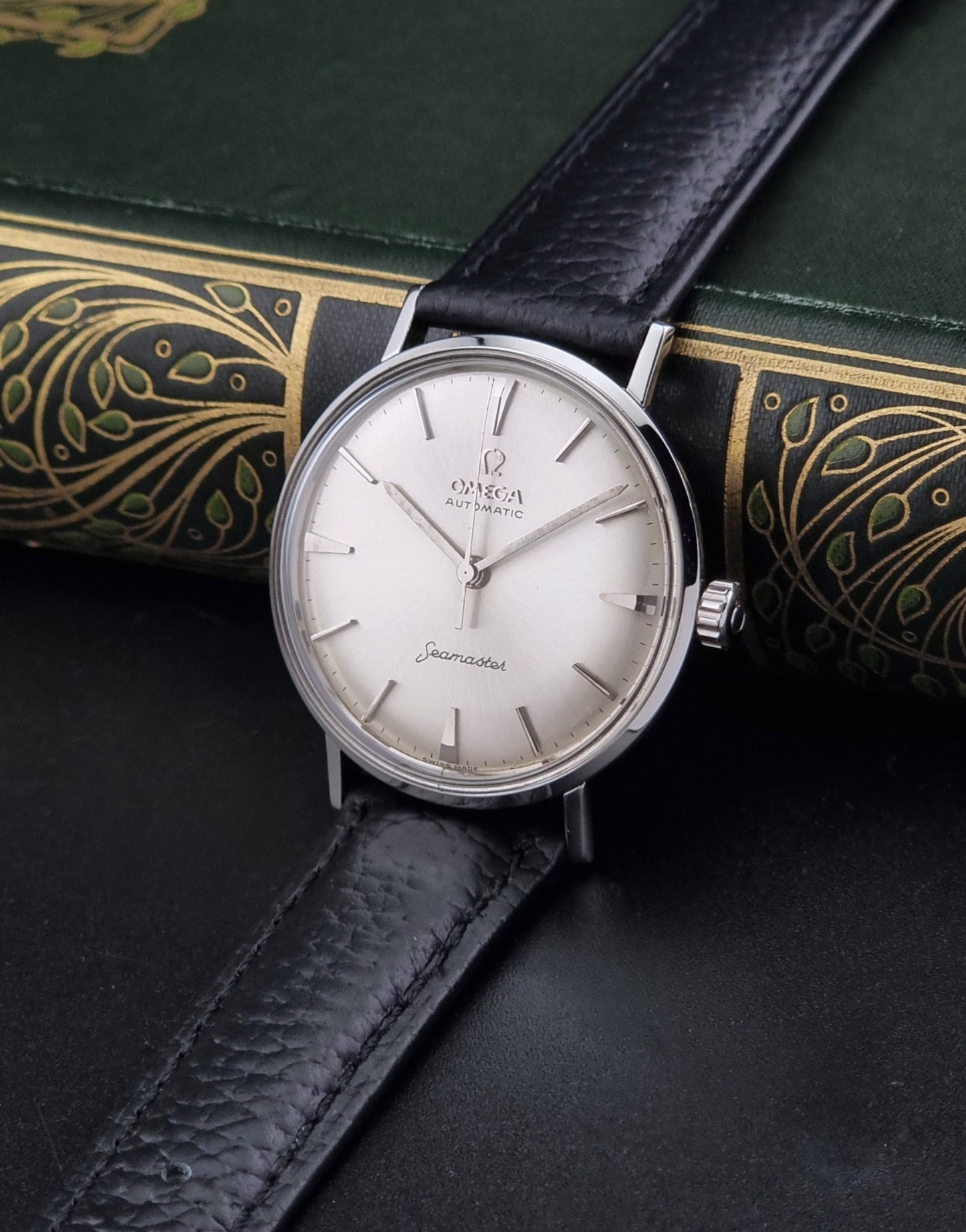 Vintage Omega Seamaster 14765 Wristwatch on a texture black leather strap on a dark background crown view