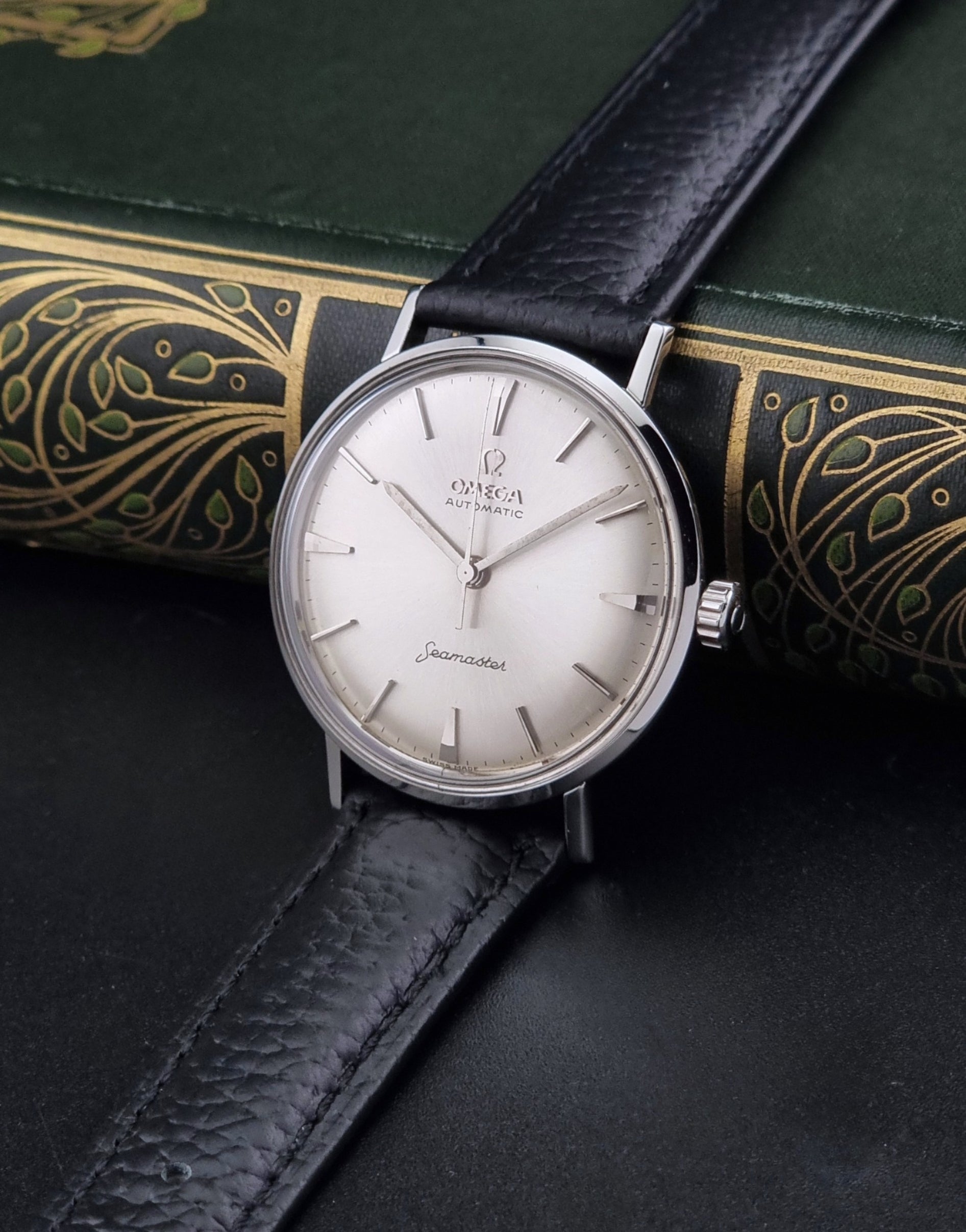 Vintage Omega Seamaster 14765 Wristwatch on a texture black leather strap on a dark background crown view