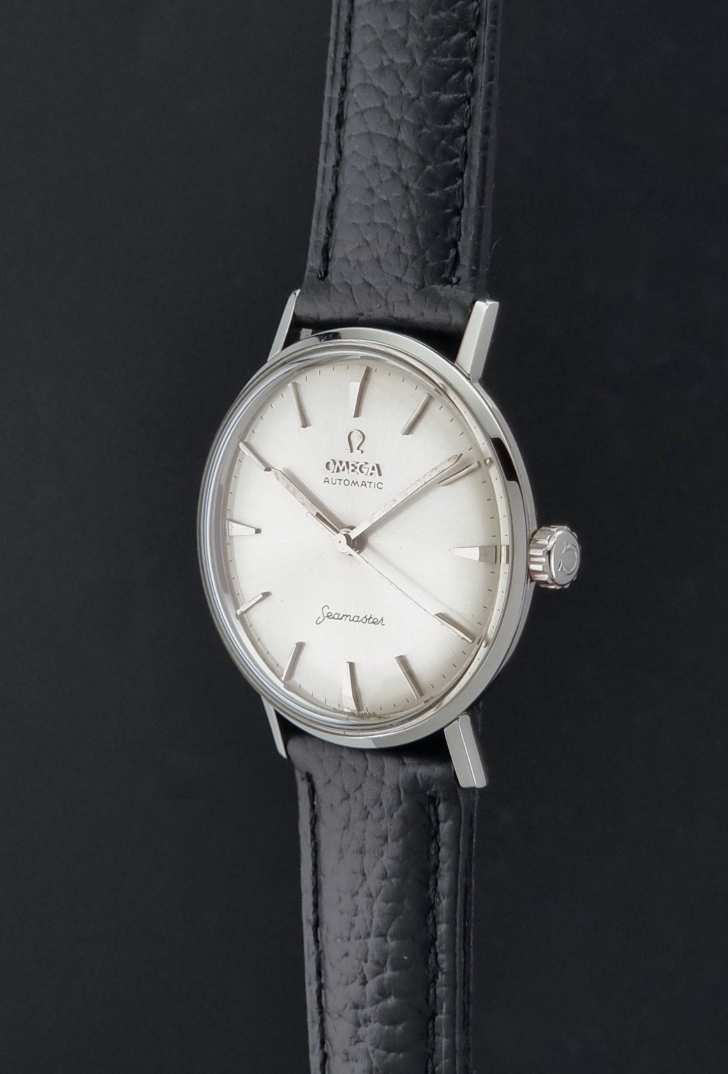 Vintage Omega Seamaster 14765 Wristwatch on a texture black leather strap on a dark background crown profile view
