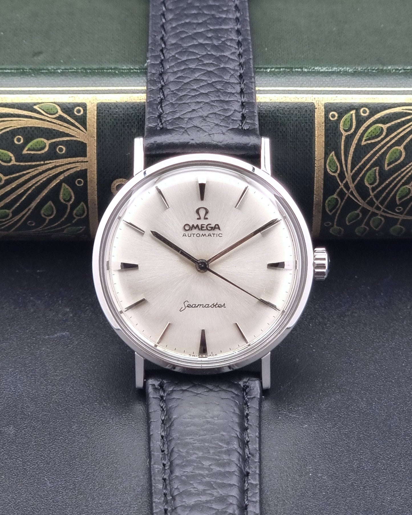 Vintage Omega Seamaster 14765 Wristwatch on a texture black leather strap on a dark background dial view