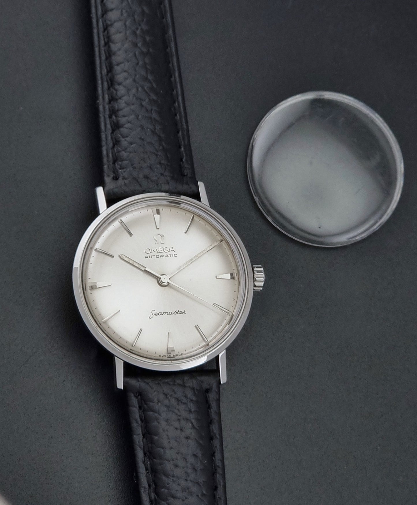 Vintage Omega Seamaster 14765 Wristwatch on a texture black leather strap on a dark background close up dial view