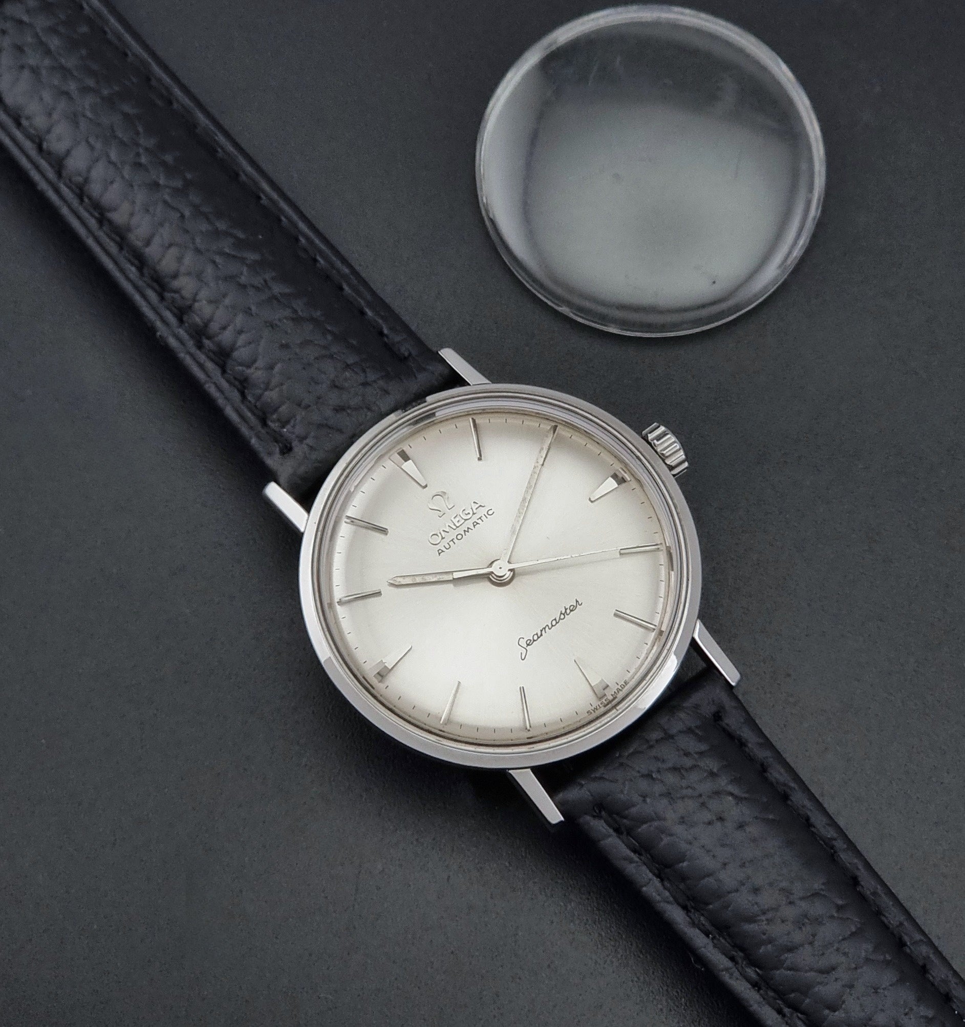Vintage Omega Seamaster 14765 Wristwatch on a texture black leather strap on a dark background dial