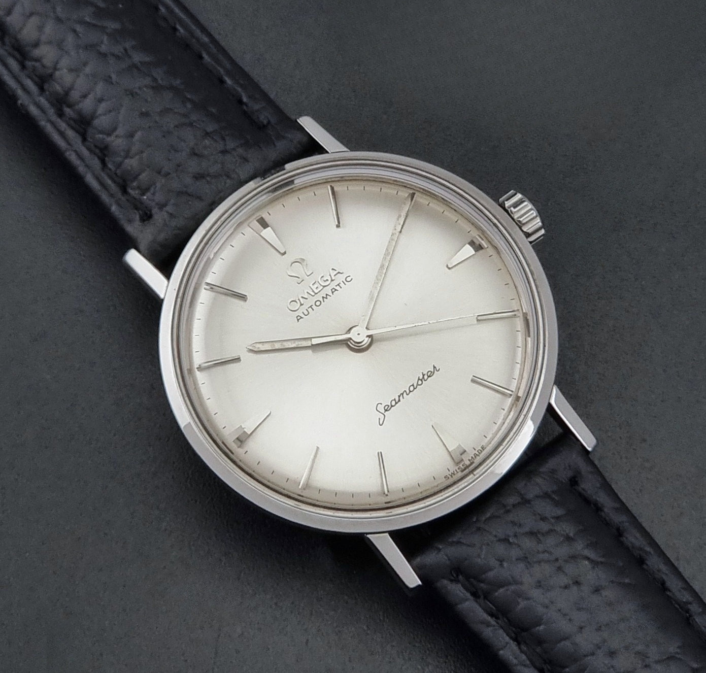 Vintage Omega Seamaster 14765 Wristwatch on a texture black leather strap on a dark background front view