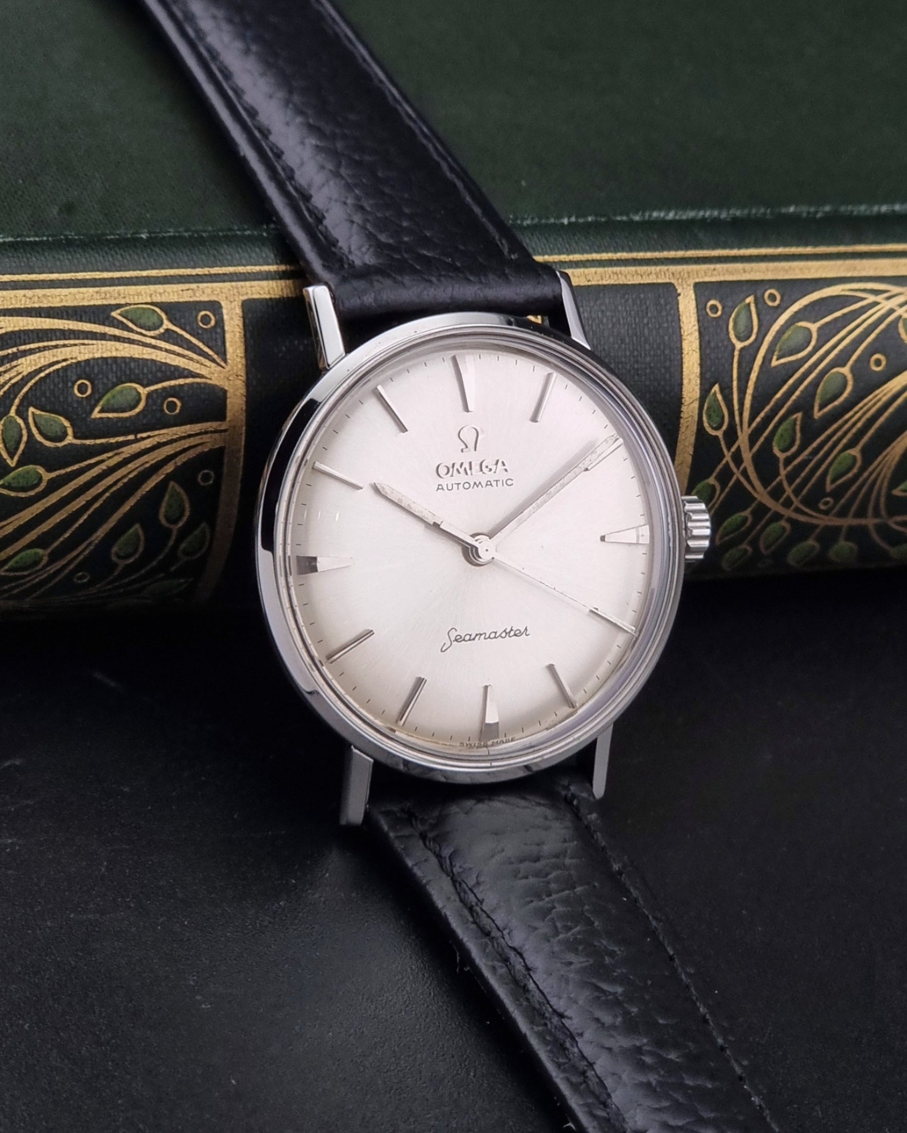 Vintage Omega Seamaster 14765 Wristwatch on a texture black leather strap on a dark background side view