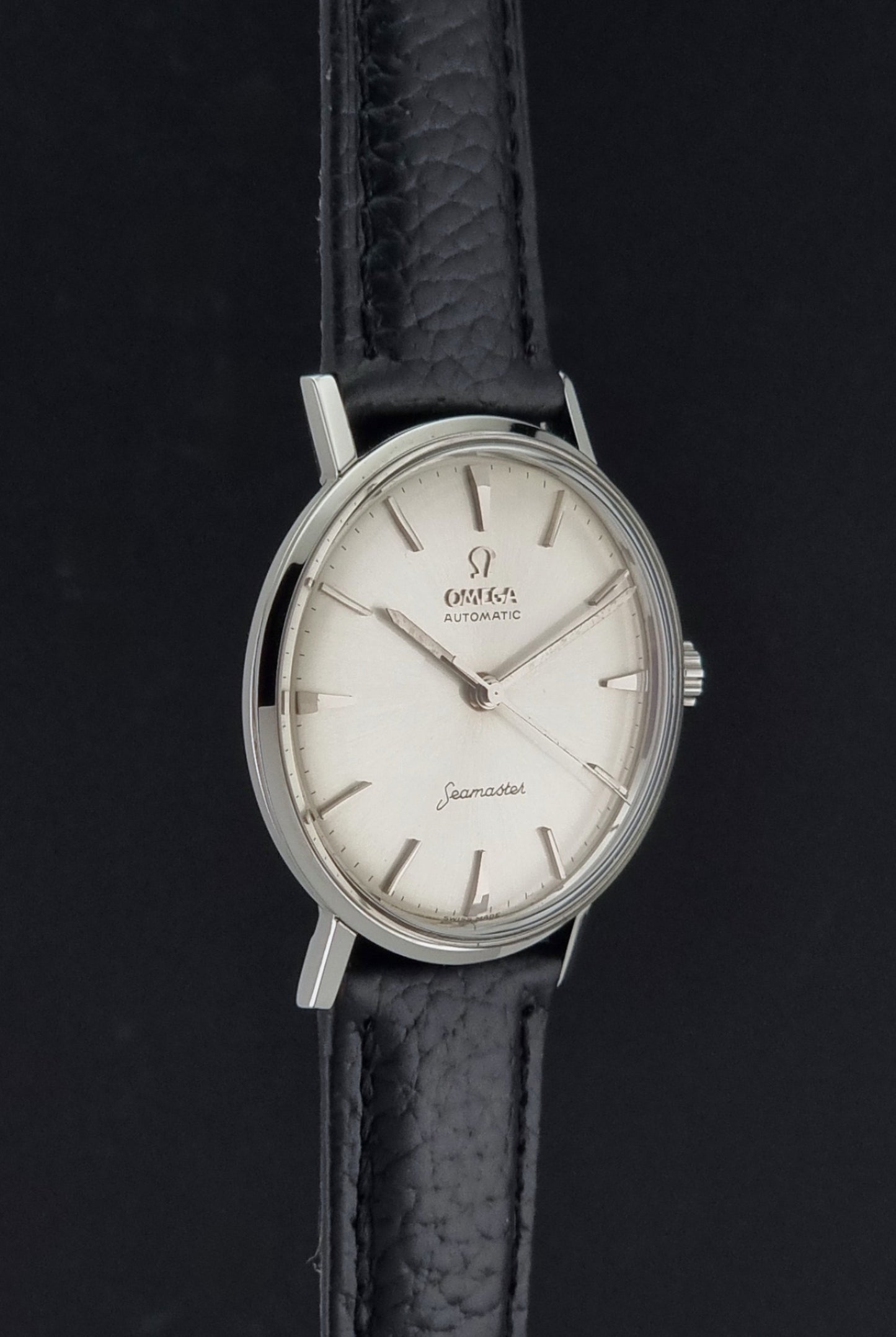 Vintage Omega Seamaster 14765 Wristwatch on a texture black leather strap on a dark background side profile view