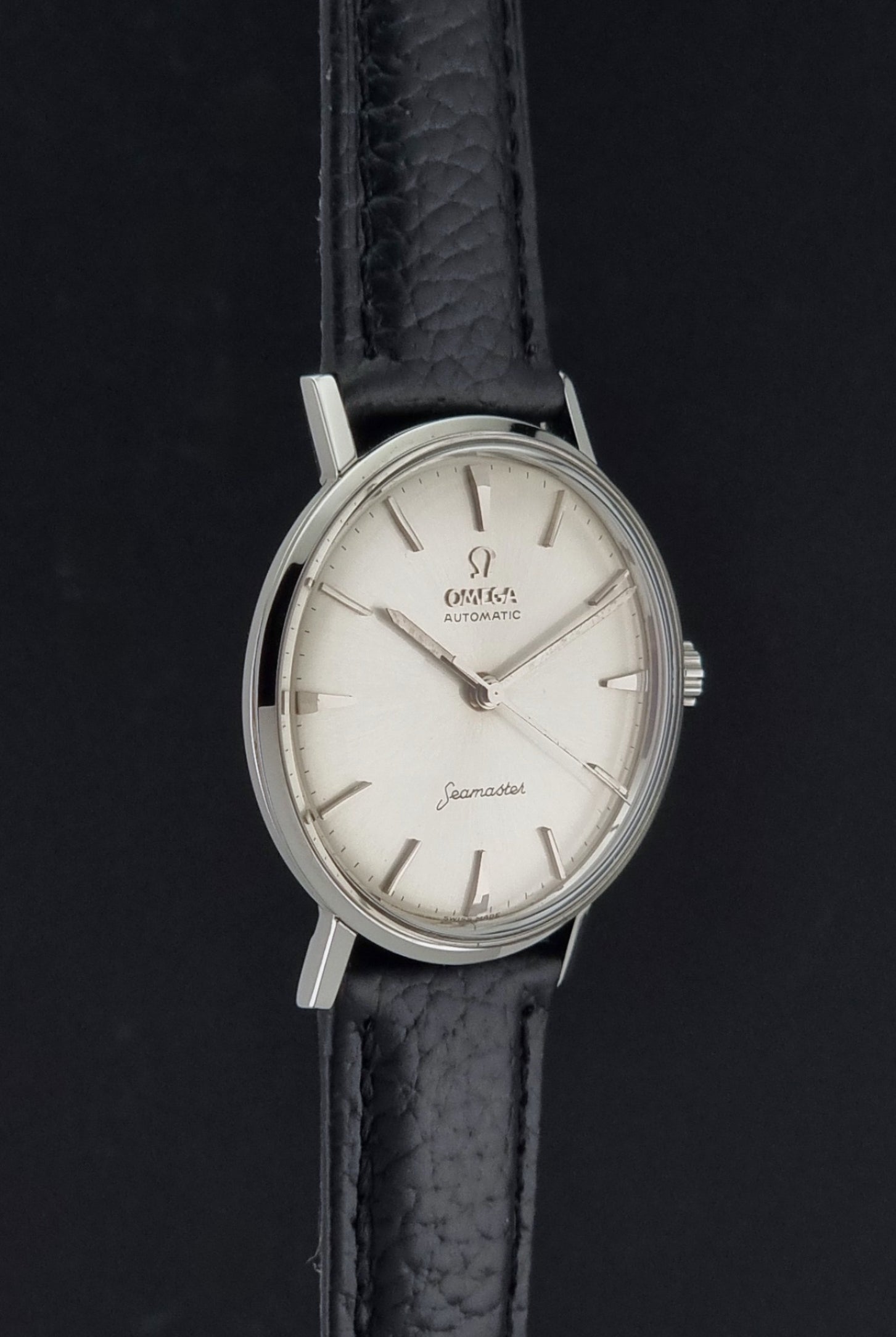 Vintage Omega Seamaster 14765 Wristwatch on a texture black leather strap on a dark background side profile view
