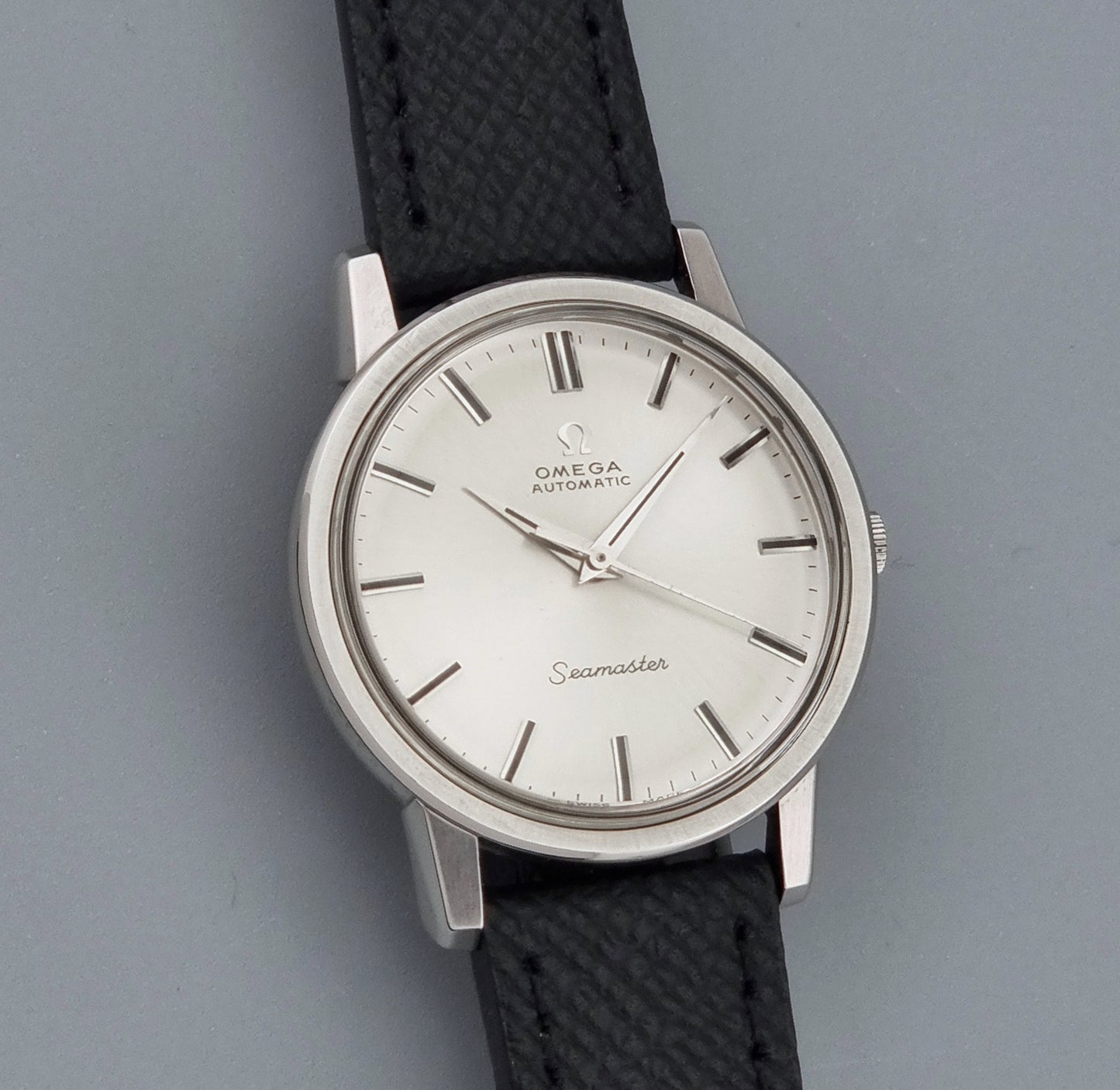 Vintage Omega Wristwatch Seamaster 165.003 with a silver-toned round case and black textured strap, shown on a gray background front view