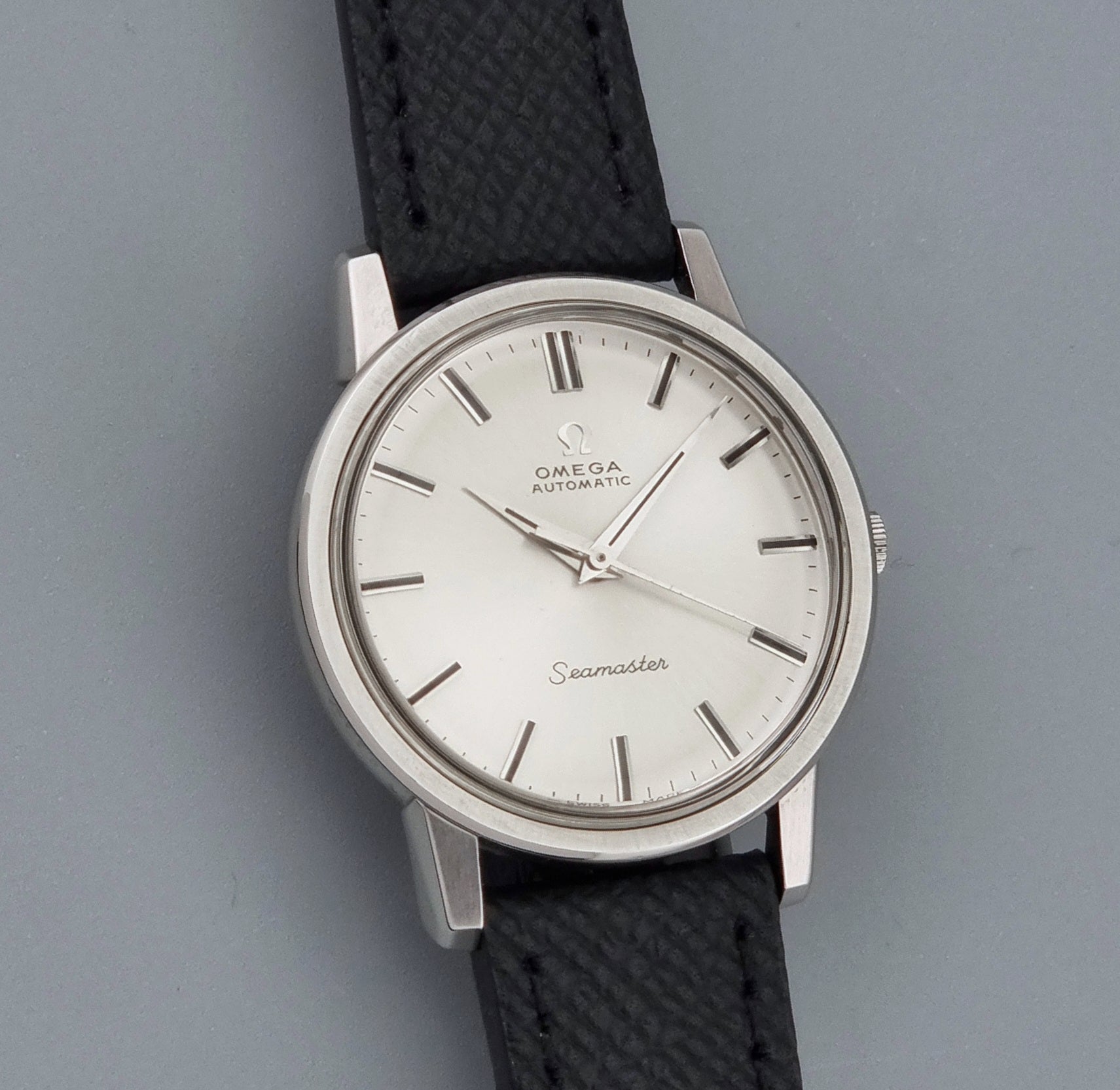 Vintage Omega Wristwatch Seamaster 165.003 with a silver-toned round case and black textured strap, shown on a gray background front view
