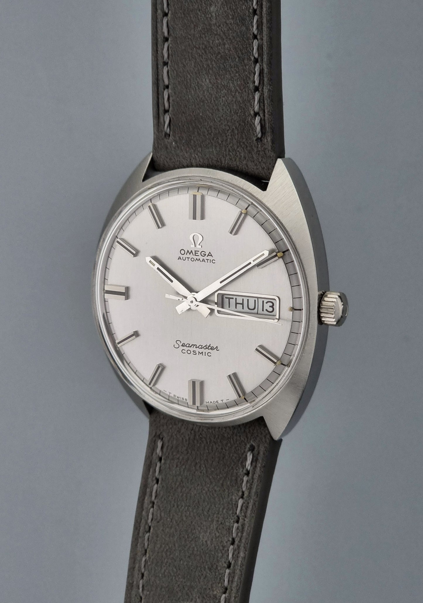 Vintage Omega Wristwatch Seamaster Cosmic 166.036 with a grey leather strap on a gray background crown side profile