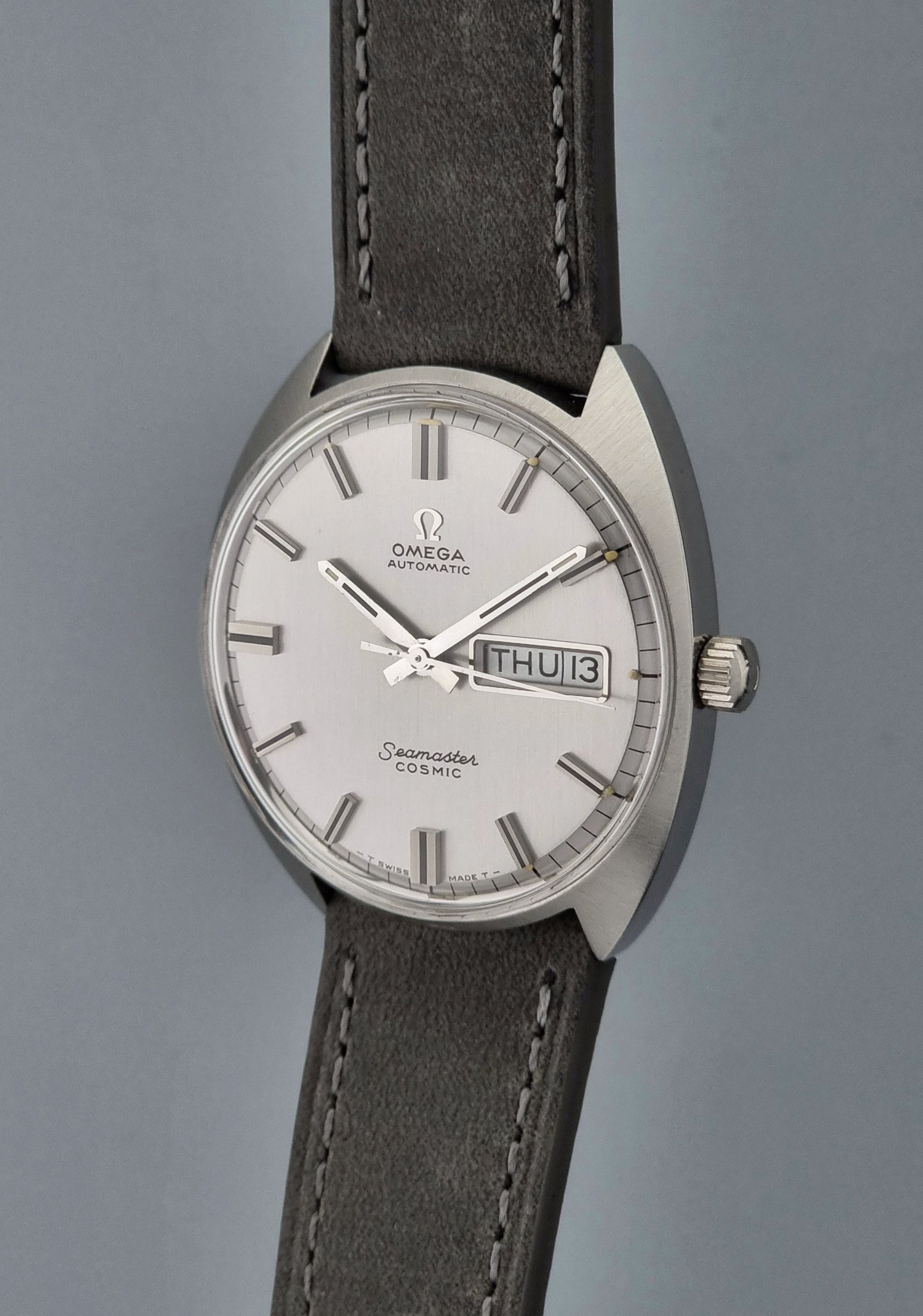 Vintage Omega Wristwatch Seamaster Cosmic 166.036 with a grey leather strap on a gray background crown side profile