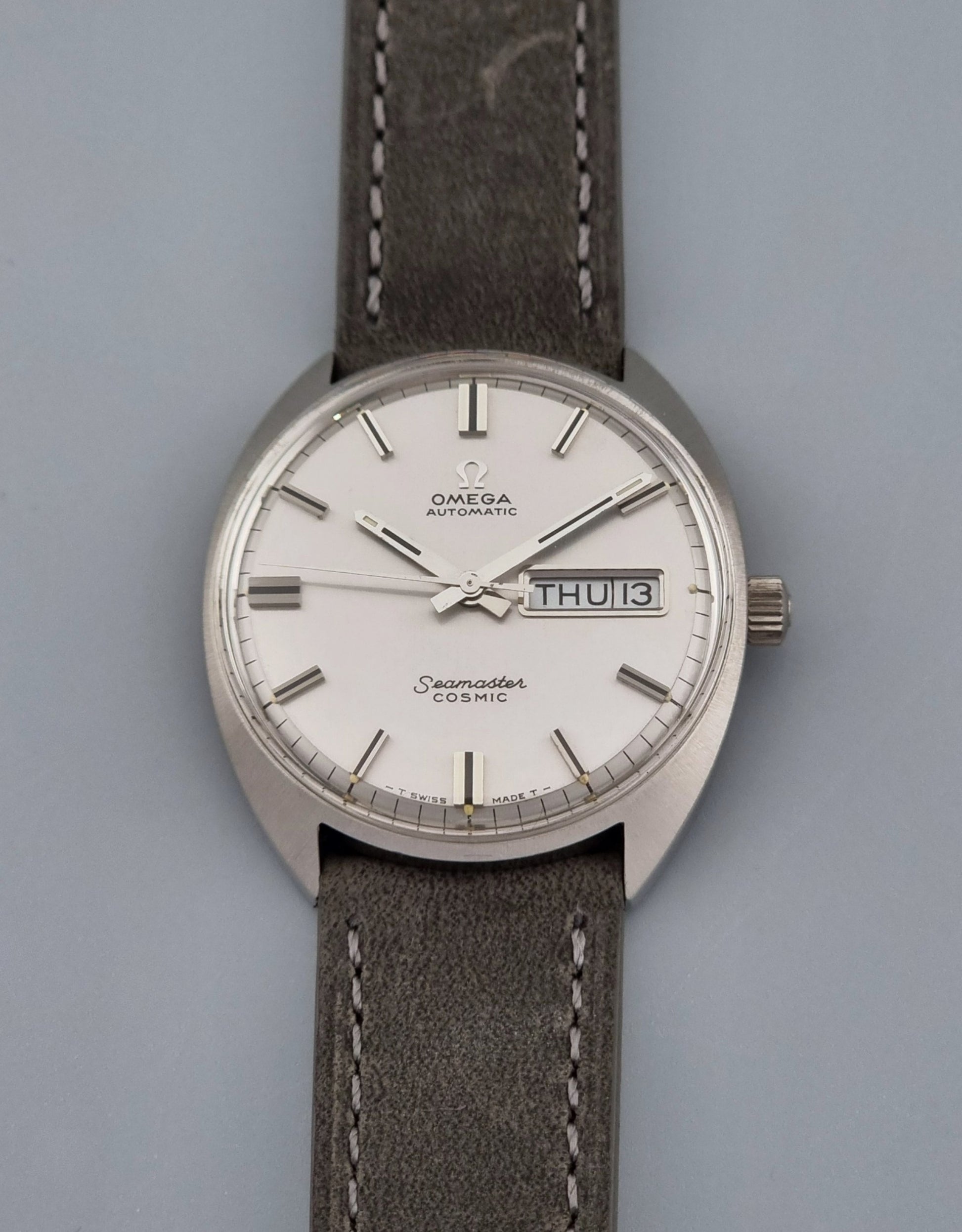 Vintage Omega Wristwatch Seamaster Cosmic 166.036 with a grey leather strap on a gray background front
