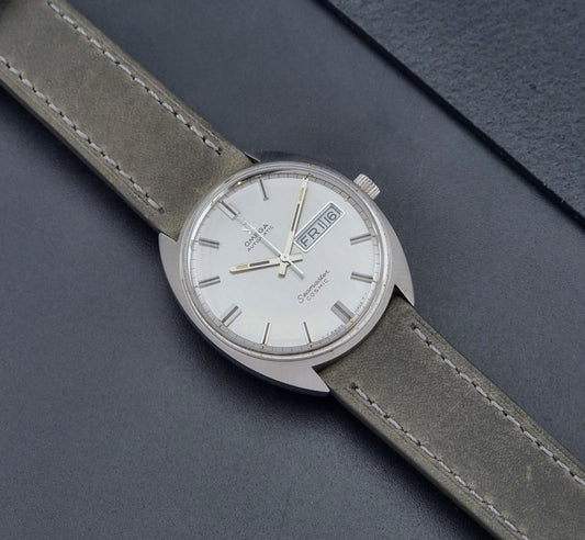 Vintage Omega Wristwatch 166.036 Seamaster Cosmic with gray strap and silver dial on a dark background dial