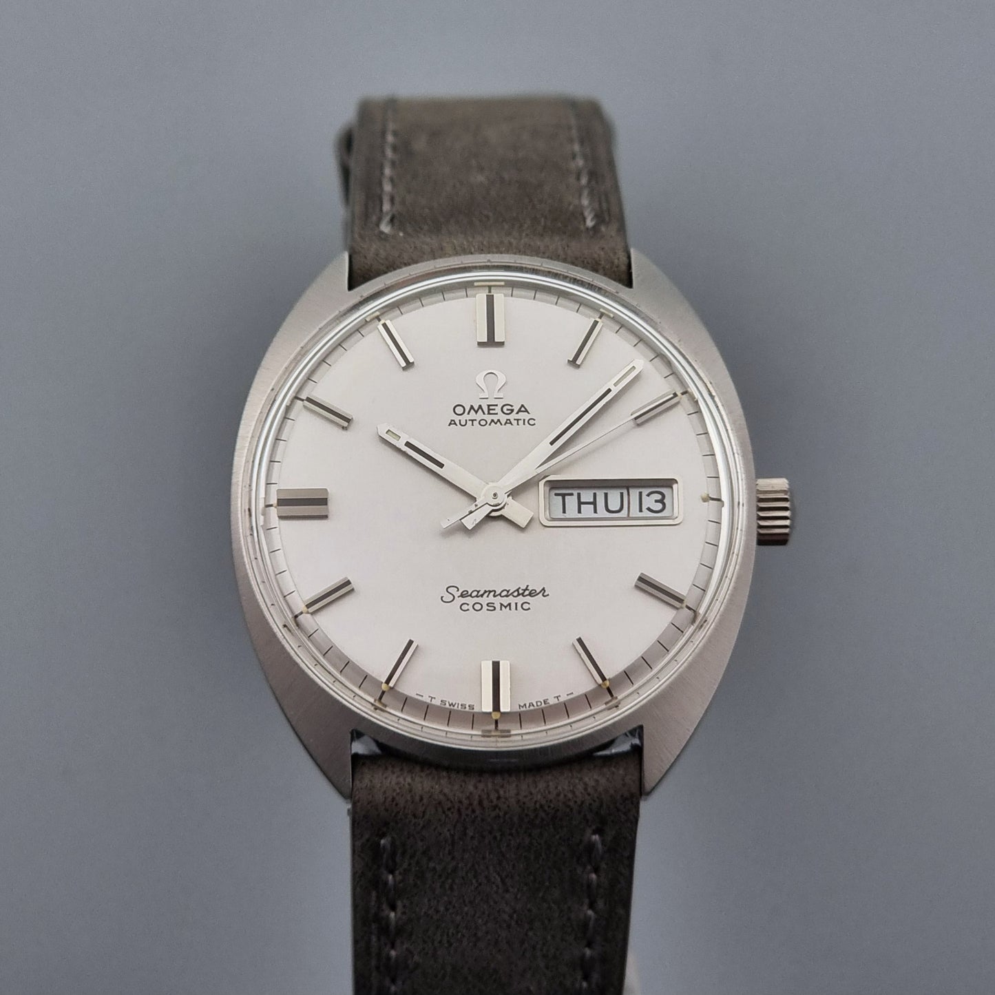 Vintage Omega Wristwatch Seamaster Cosmic 166.036 with a grey leather strap on a gray background close up