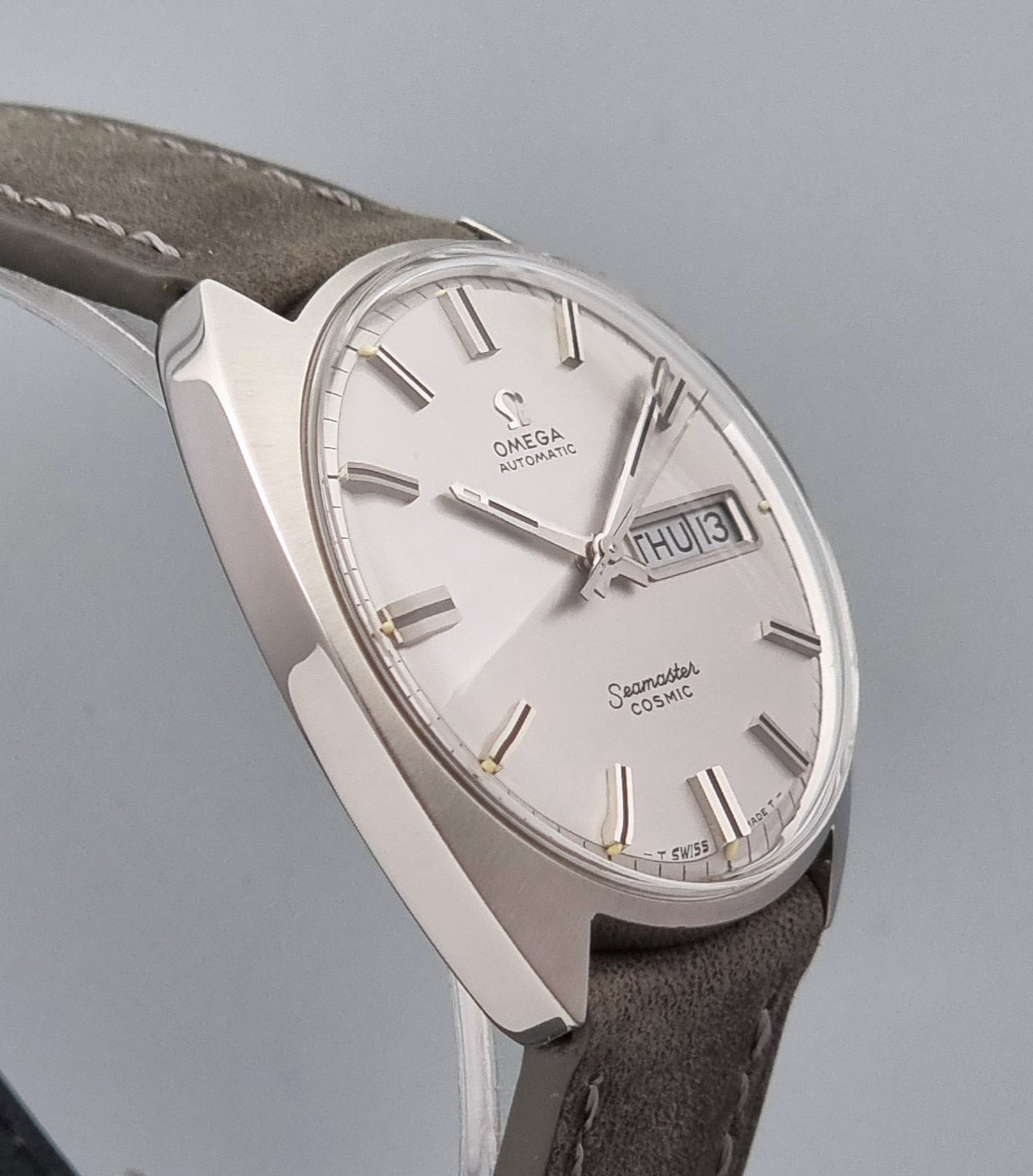 Vintage Omega Wristwatch Seamaster Cosmic 166.036 with a grey leather strap on a gray background profile view