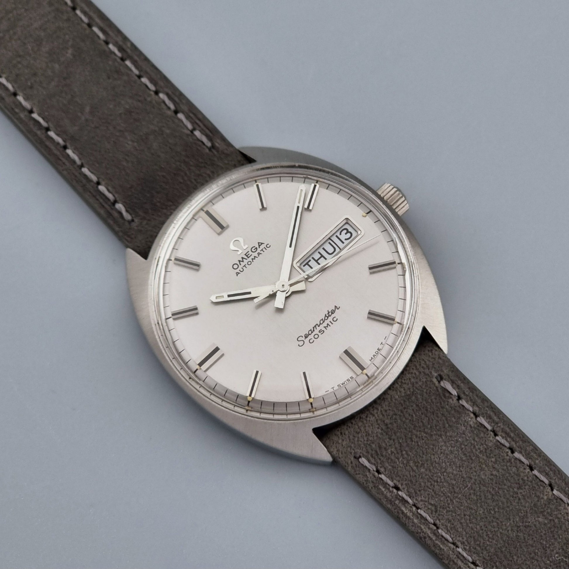 Vintage Omega Wristwatch Seamaster Cosmic 166.036 with a grey leather strap on a gray background font view