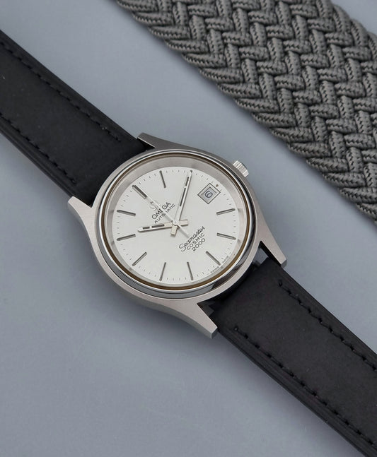 Vintage Omega Wristwatch Seamaster Cosmic 2000 Jumbo 166.128 with black leather strap and silver case on a gray background dial